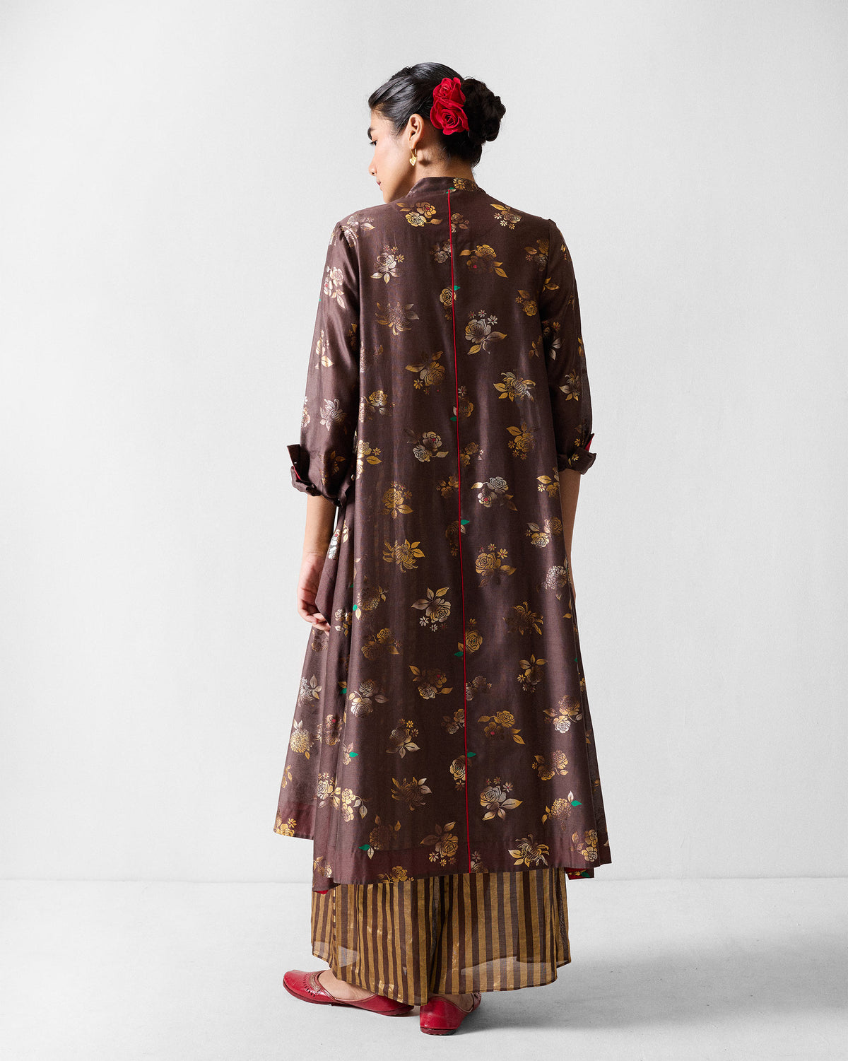 Back of a brown gold-print kurta with red centre piping.