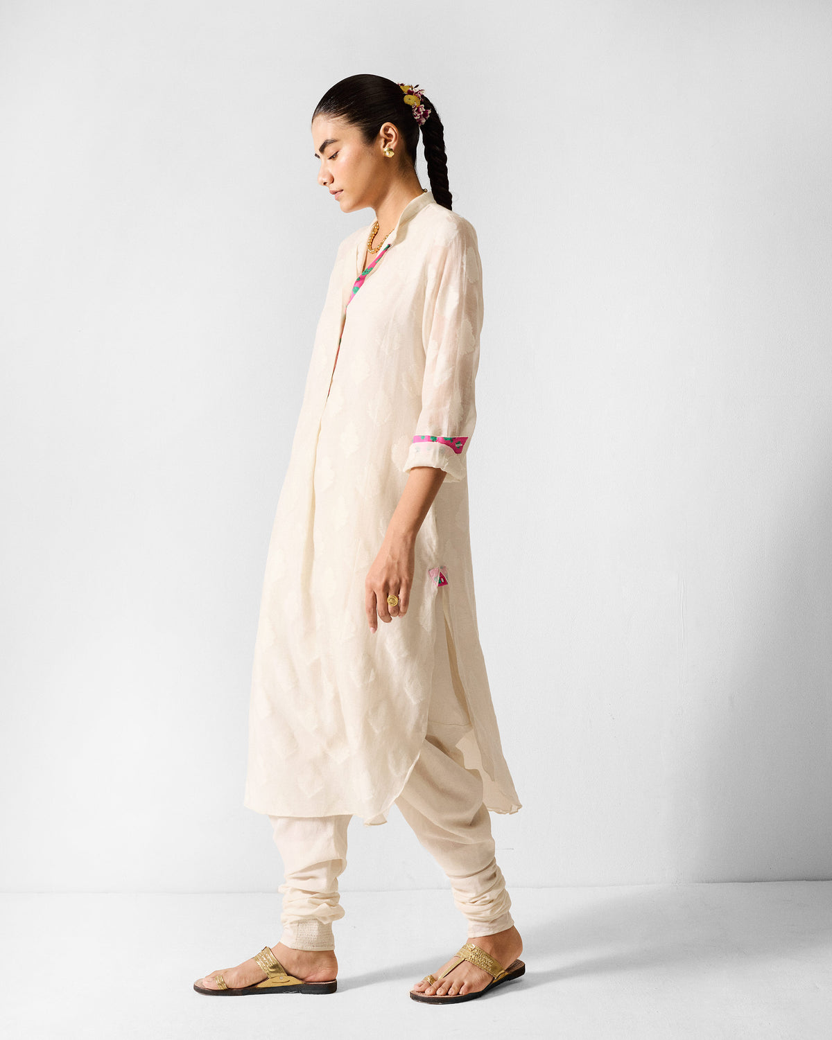 Side view of an ivory long kurta with pink and teal neckline trim.