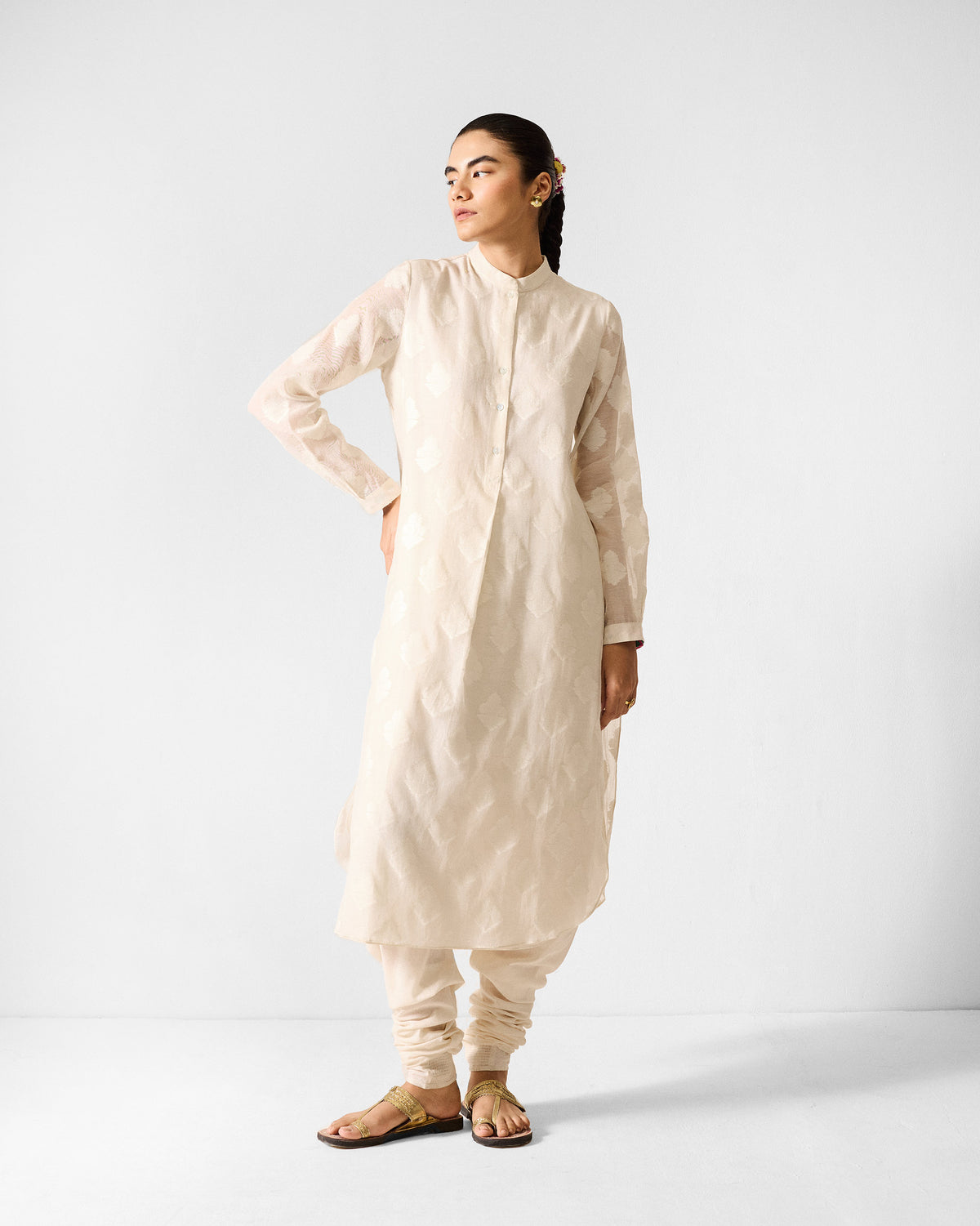 Person wearing an ivory long kurta with a tonal leaf buta pattern.
