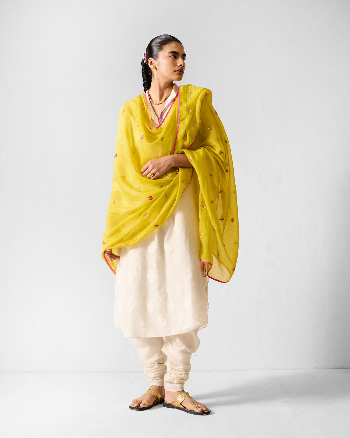 Person wearing an ivory long kurta with a lime yellow embroidered dupatta.
