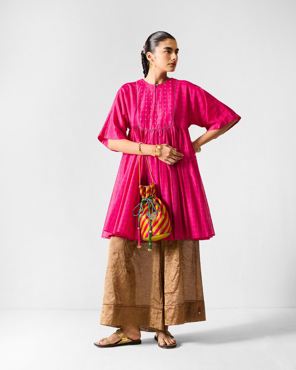 Person wearing a fuchsia Luna Afghan Kurta with a gold embroidered bib.