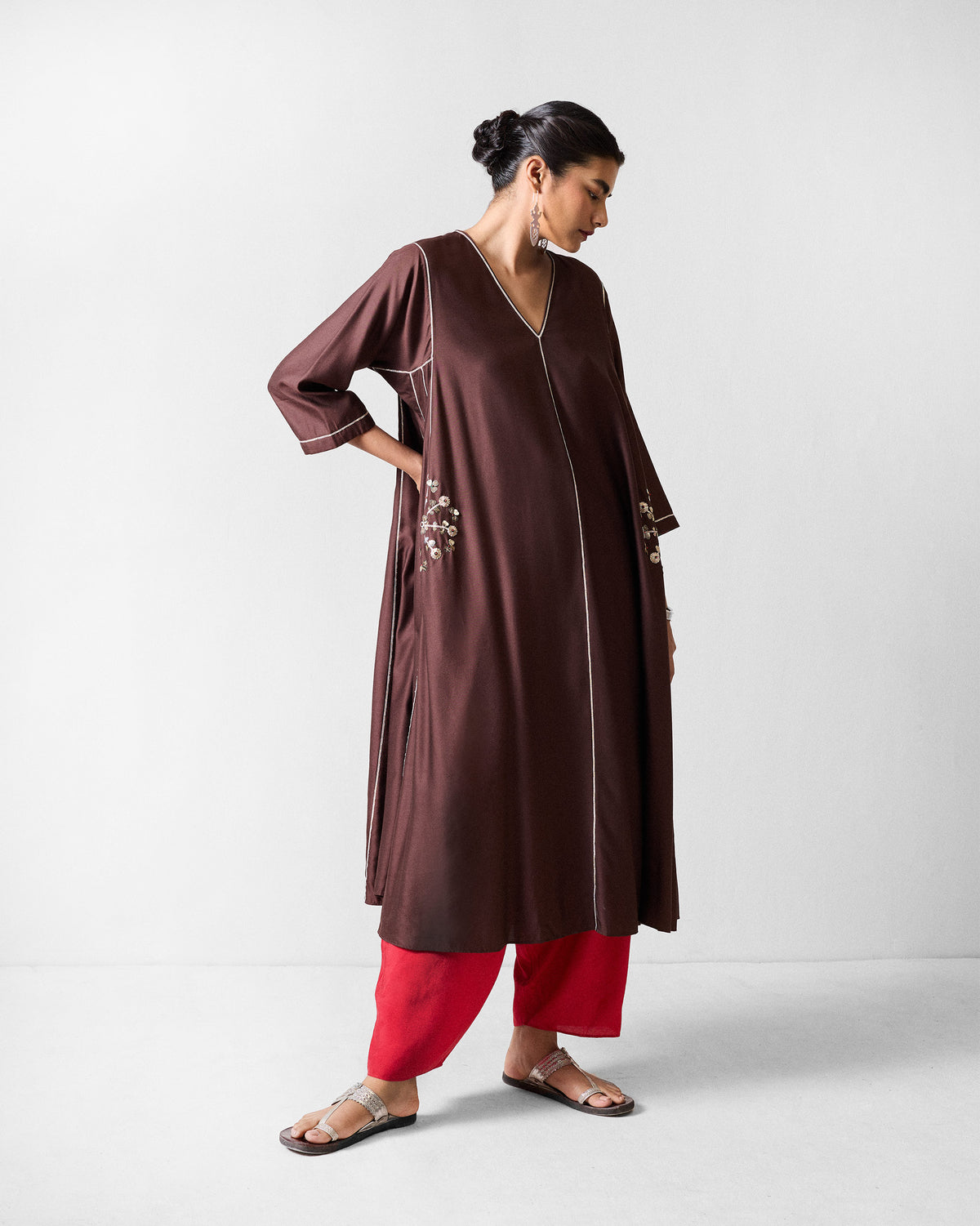 Person wearing a chocolate brown Aheli kurta with white piping and floral embroidery.