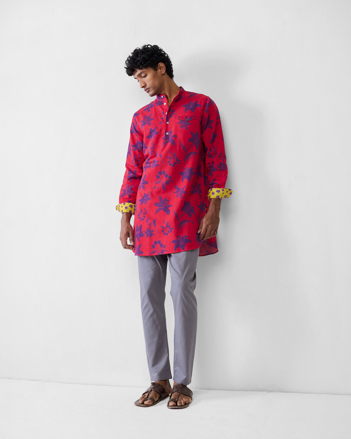 Person wearing a red Fort kurta with a purple lily print and yellow cuff lining.