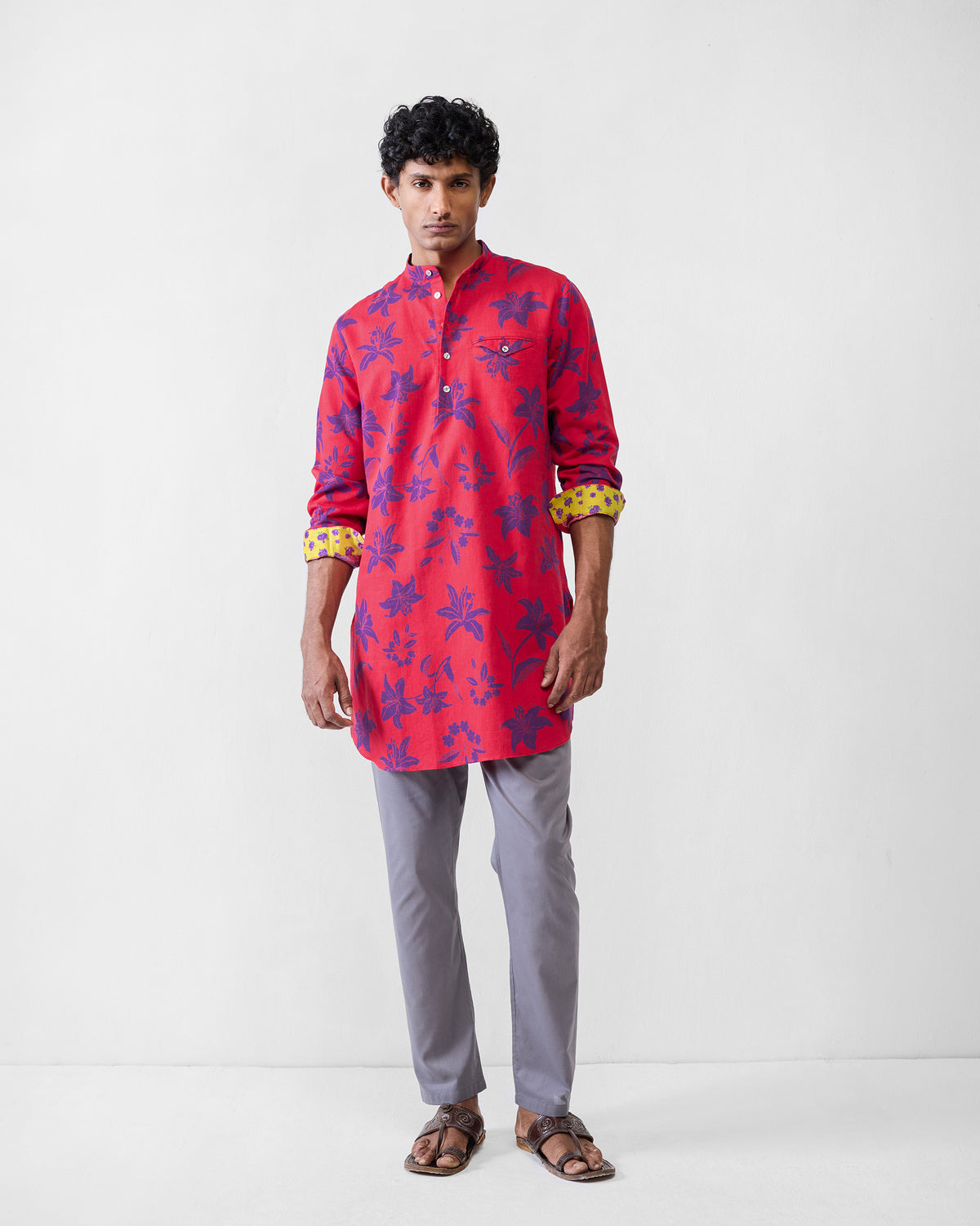 Person wearing a red Fort kurta with purple lilies and yellow cuff lining.