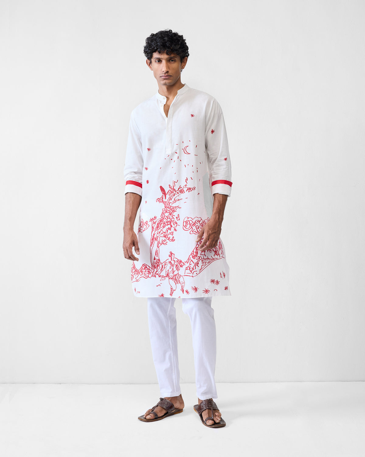 Person wearing a white Neckband Kurta with a red landscape print and red cuff bands.