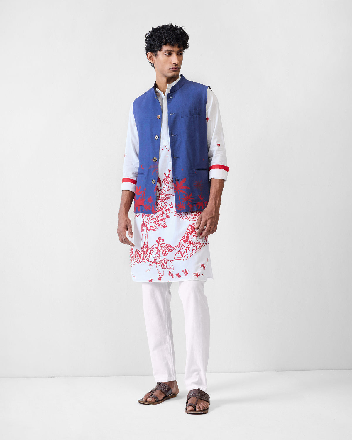 Person wearing a white Neckband Kurta with a red landscape print under a blue waistcoat.