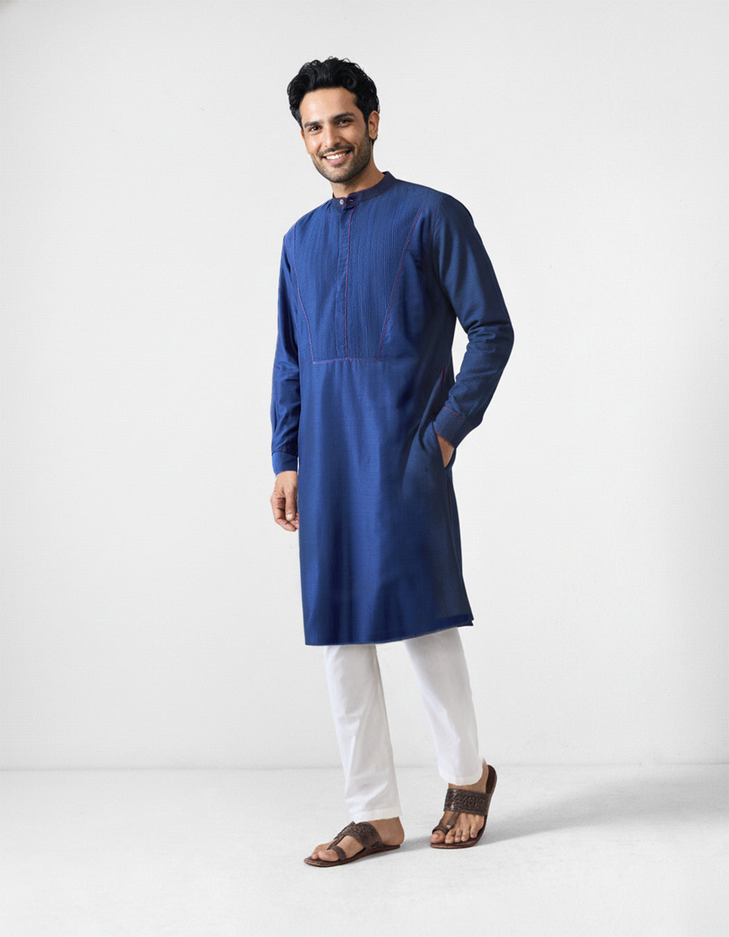 Person wearing a navy Talha kurta with a pintuck bib and red stitching.