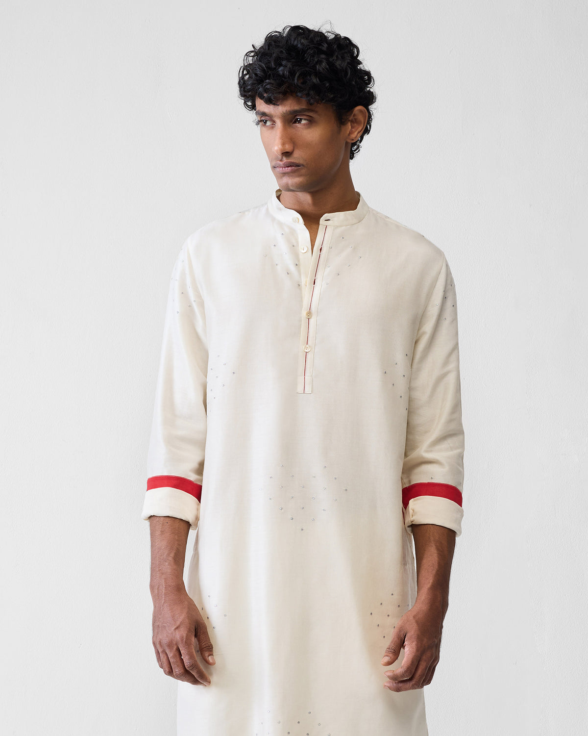 Person wearing an ivory astral kurta with silver heart embroidery and red cuffs.