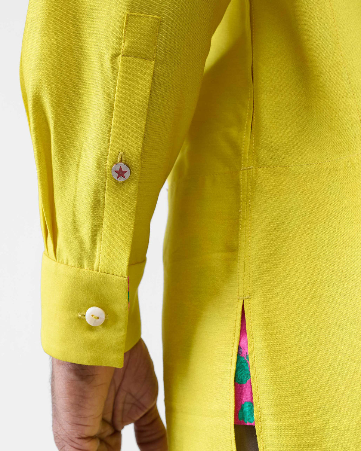 Close-up of a chartreuse Bouquet kurta cuff with a red star button.