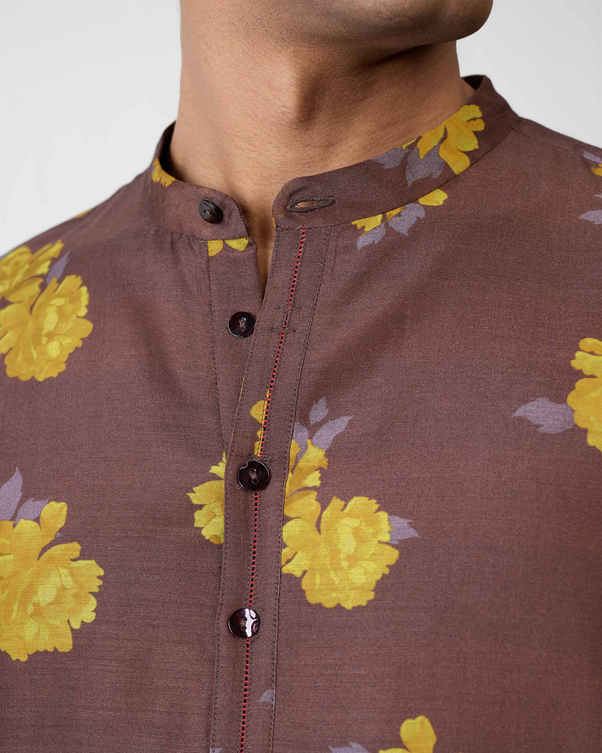 Close-up of a brown Astral kurta collar with yellow floral print and red placket stitching.