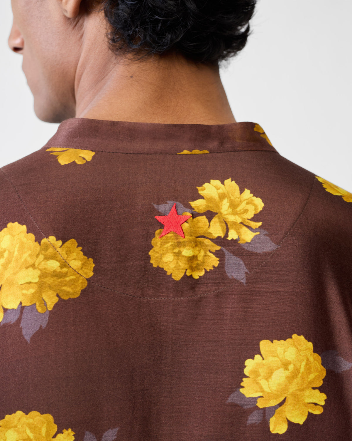 Close-up of a red star on the back of a brown Astral kurta with yellow flowers.