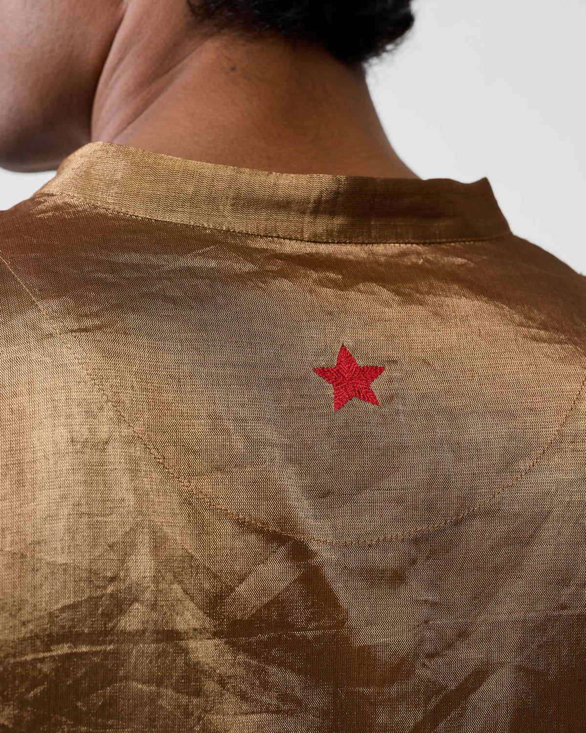 Close-up of a red star on the back of a gold Chandni Chowk kurta.