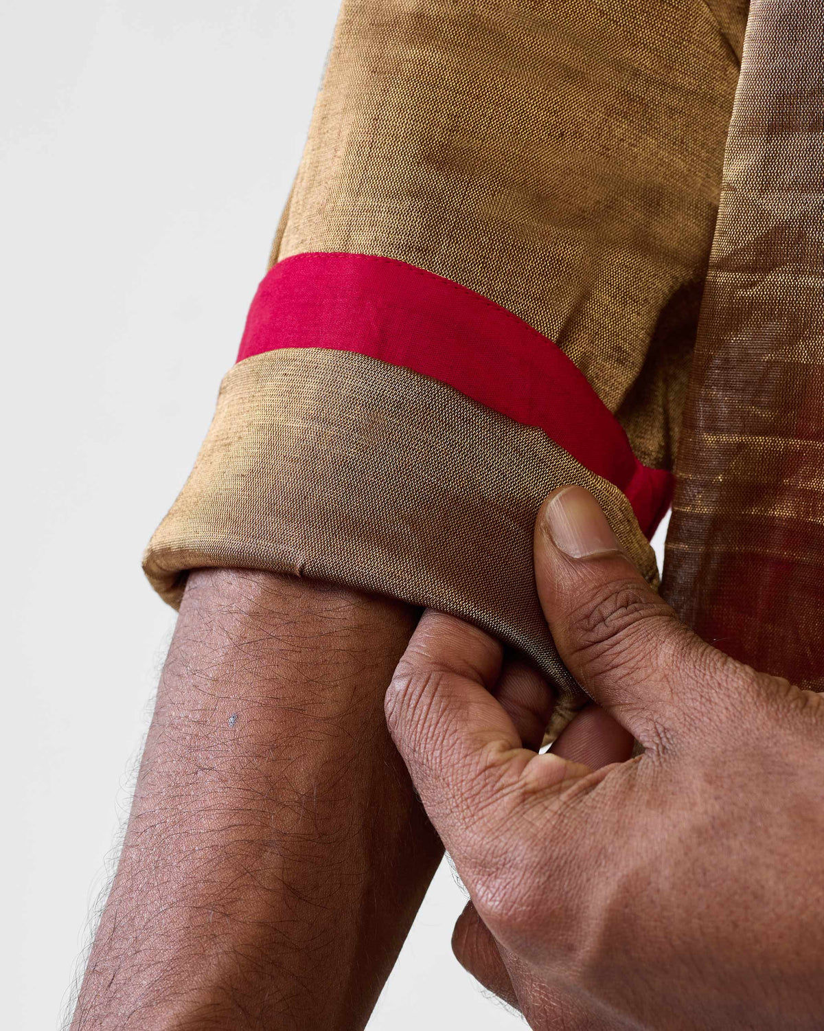 Close-up of a gold Chandni Chowk kurta sleeve with red lining.