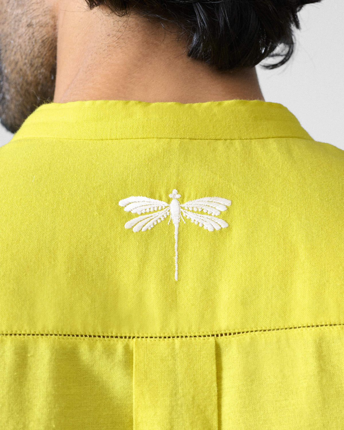 Close-up of a chartreuse Ibn Kurta back showing a white dragonfly embroidery.