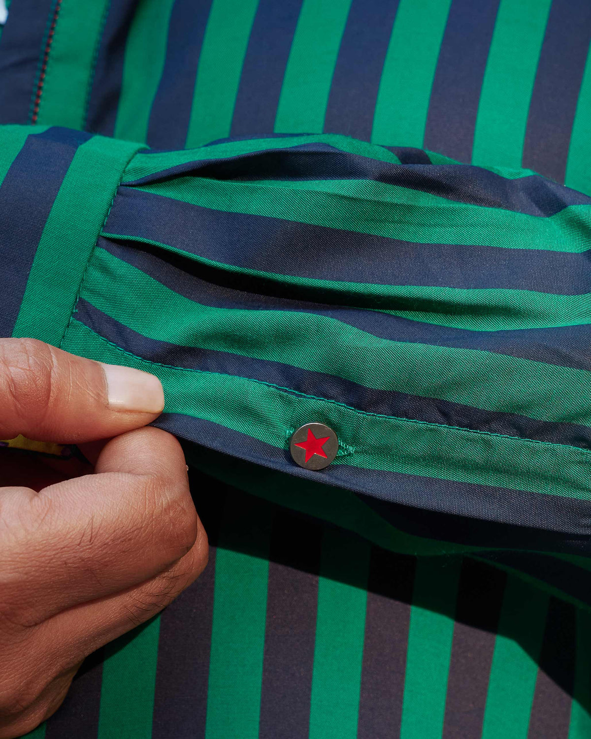 Close-up of a Gala Kurta cuff with green and navy stripes and a star button.