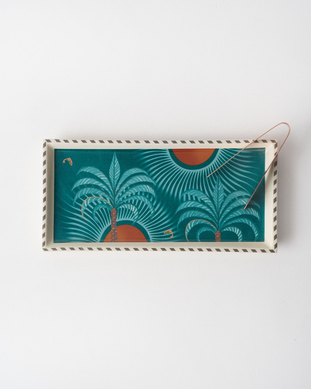 Rectangular Caden tray with palm trees, sun motifs, and copper tongs.