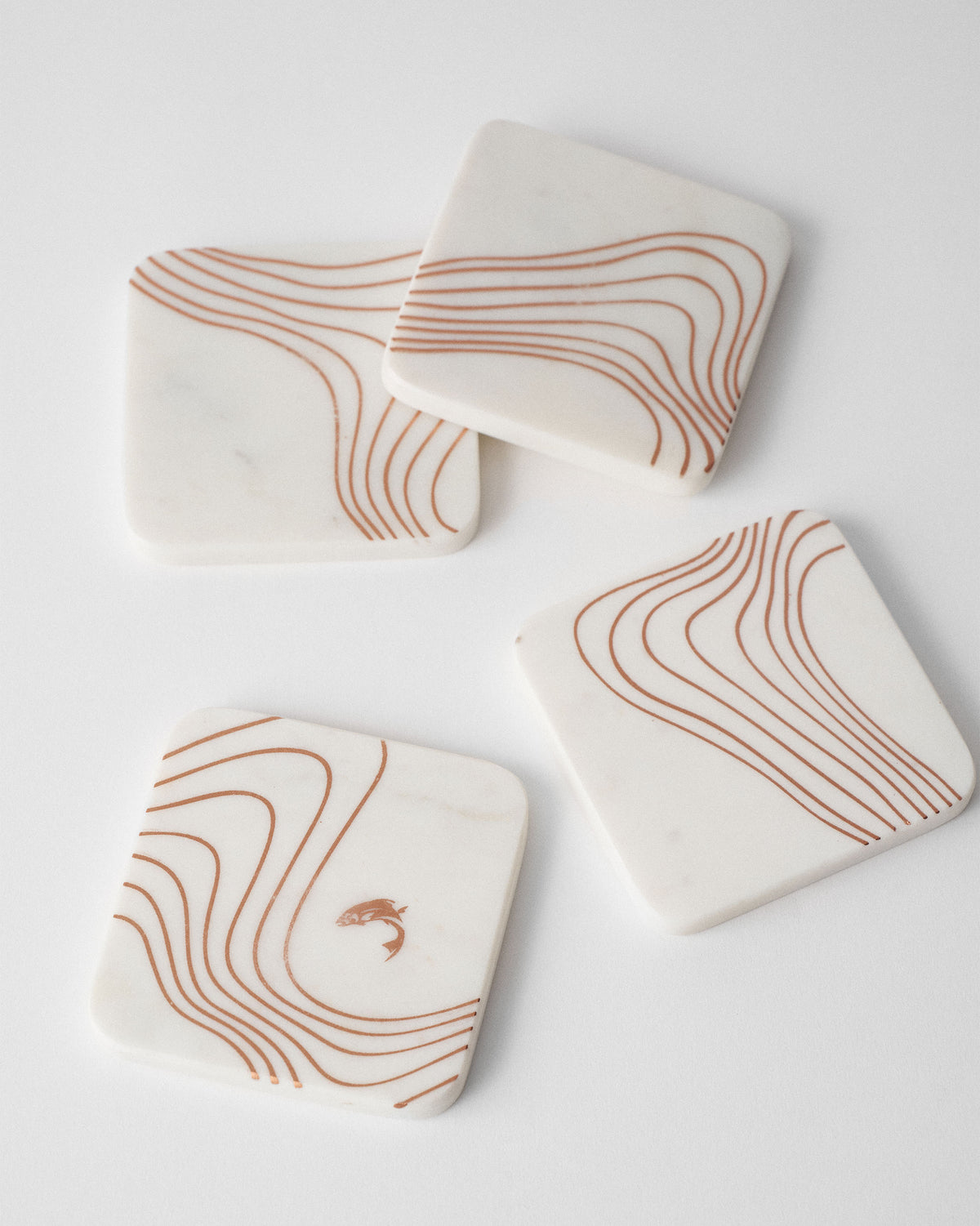 Four square marble Dusk coasters with copper contour lines.