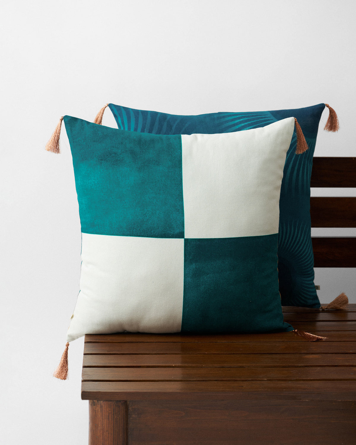 Lumen Cushion Cover in teal and cream colour blocks on a wooden bench.