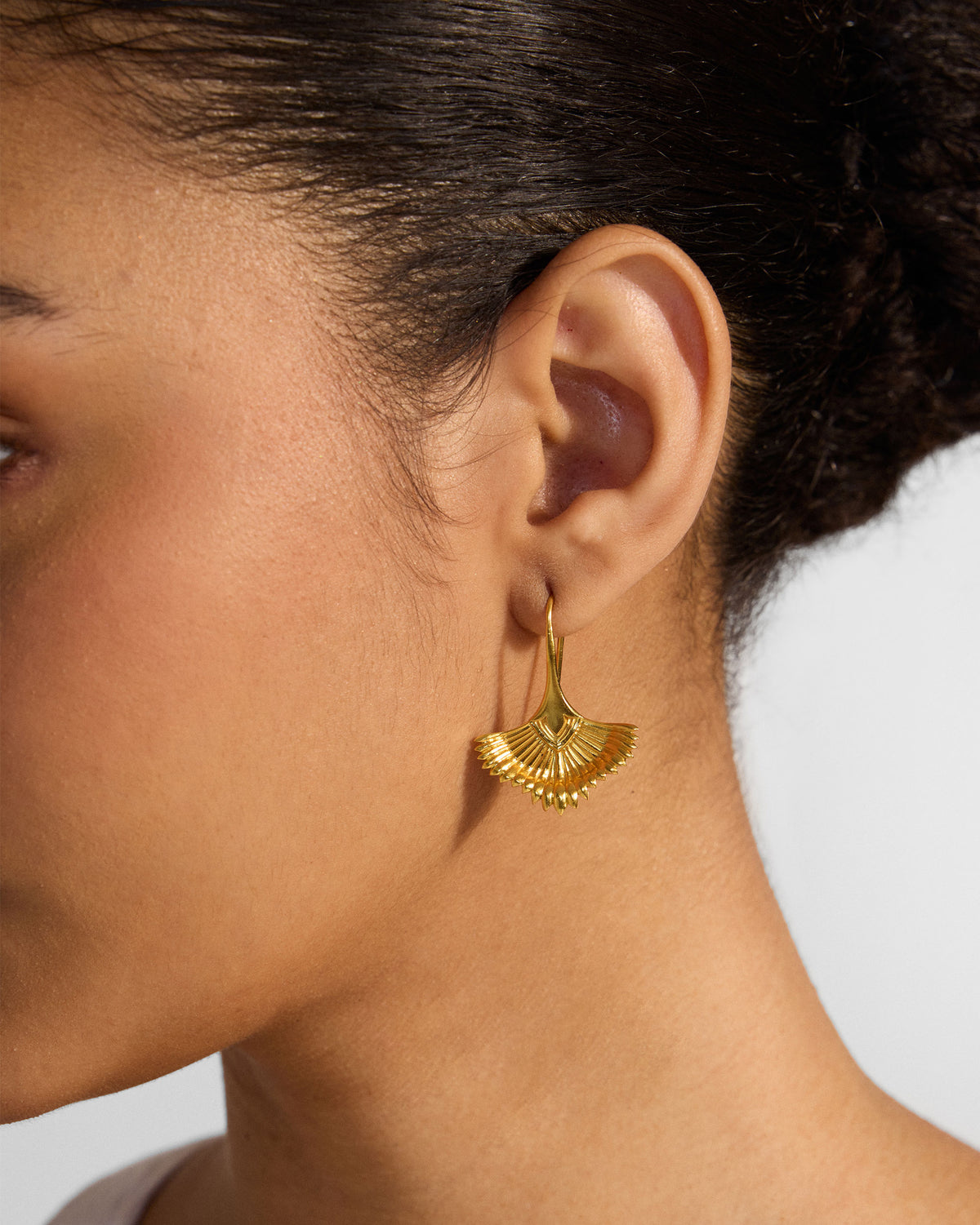 Side profile of a gold Festive Palm dangler with ridged fan shape on a person.