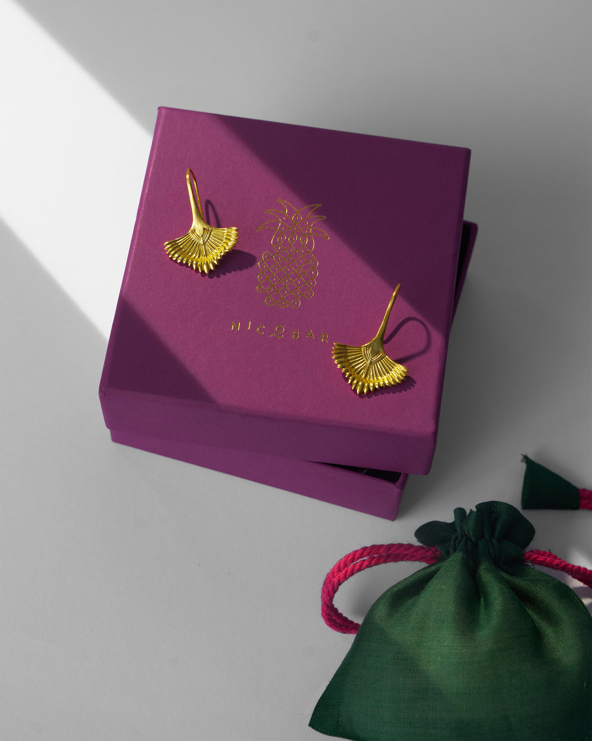 Gold Festive Palm danglers on a magenta Nicobar box with a green pouch.