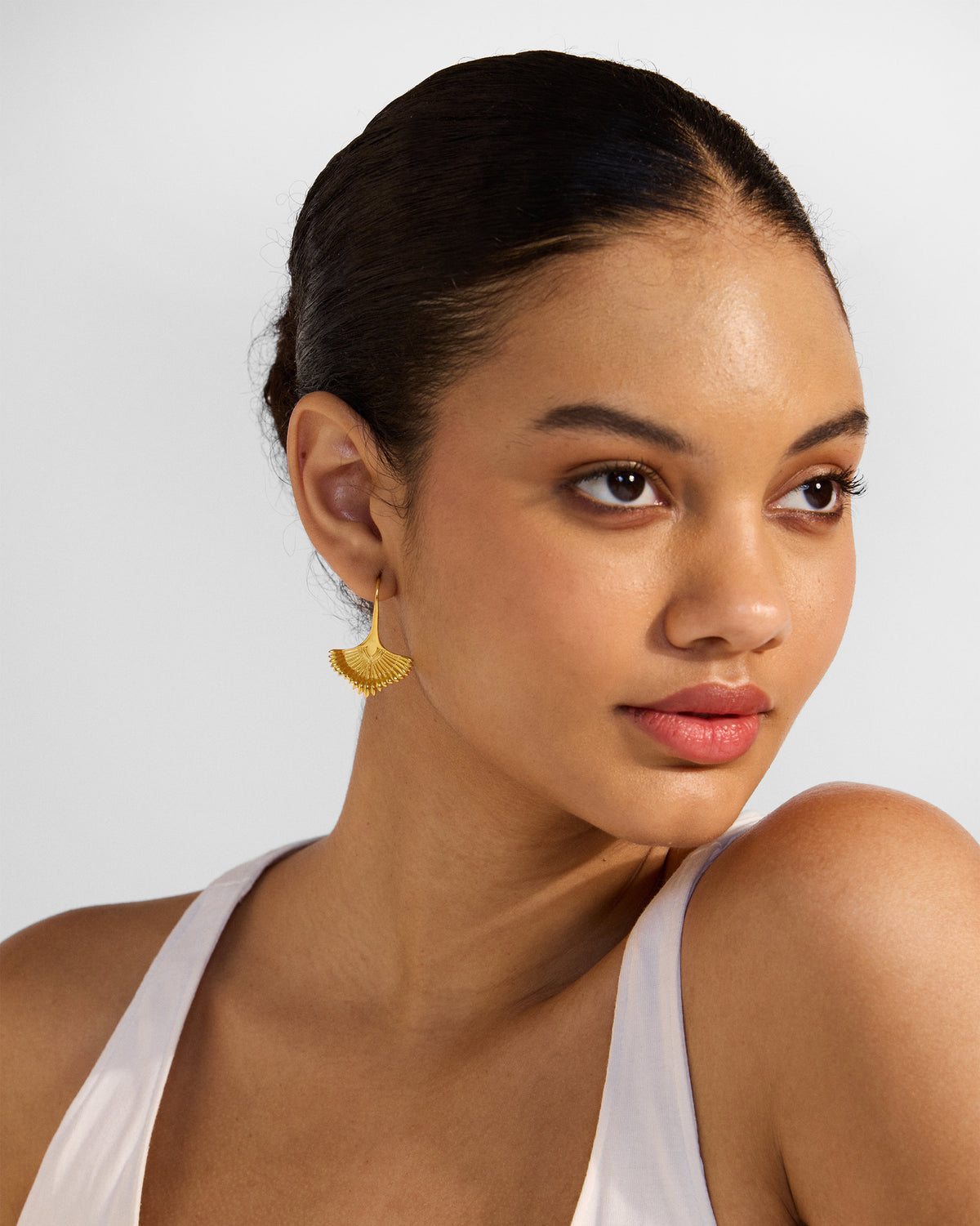 Person wearing a gold Festive Palm dangler with a ridged fan shape.