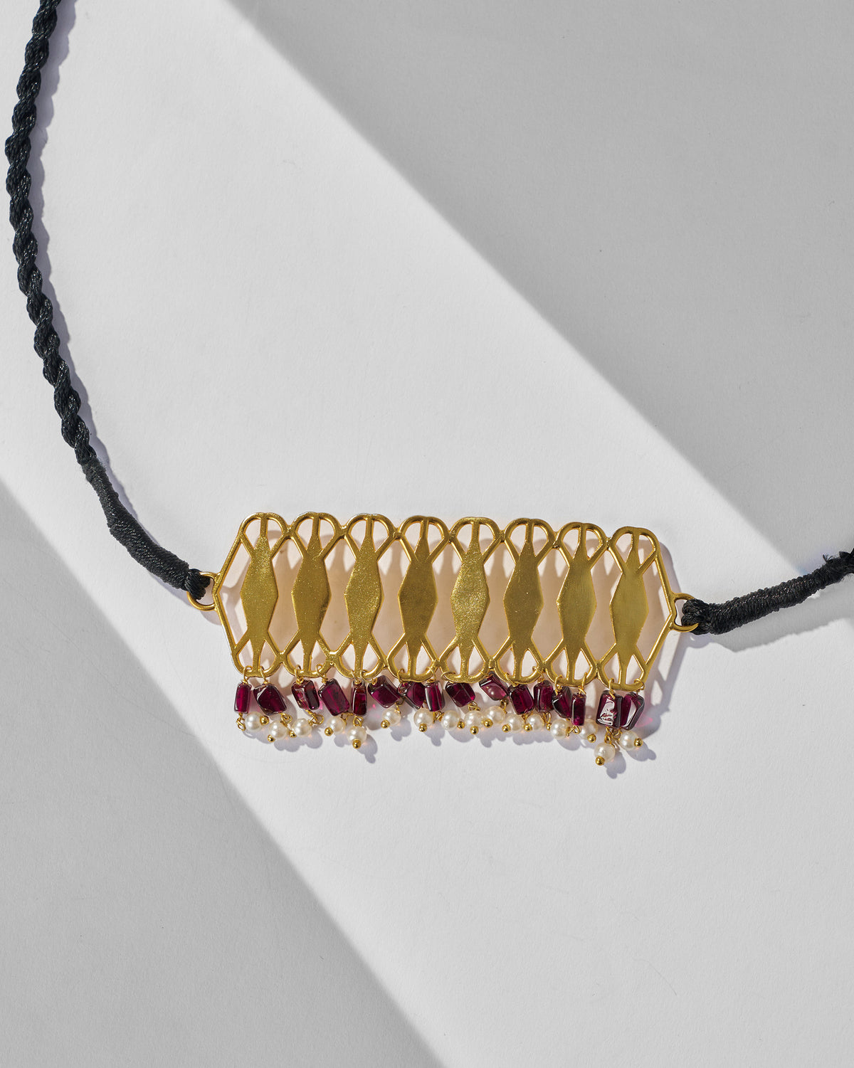 Close-up of the gold Barfi lattice plate with garnet and pearl fringe.