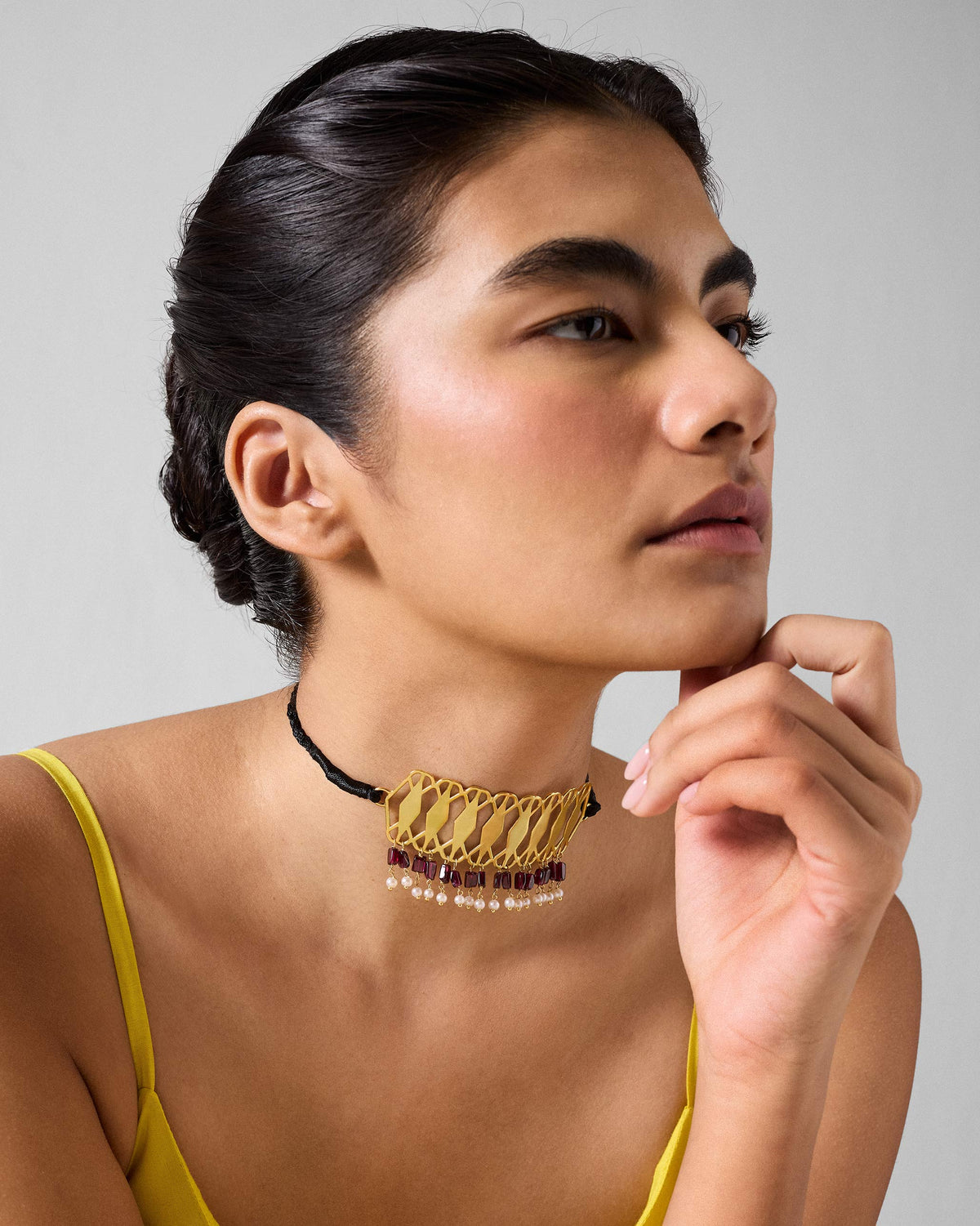 Person wearing a gold Barfi choker with garnet and pearl fringe.