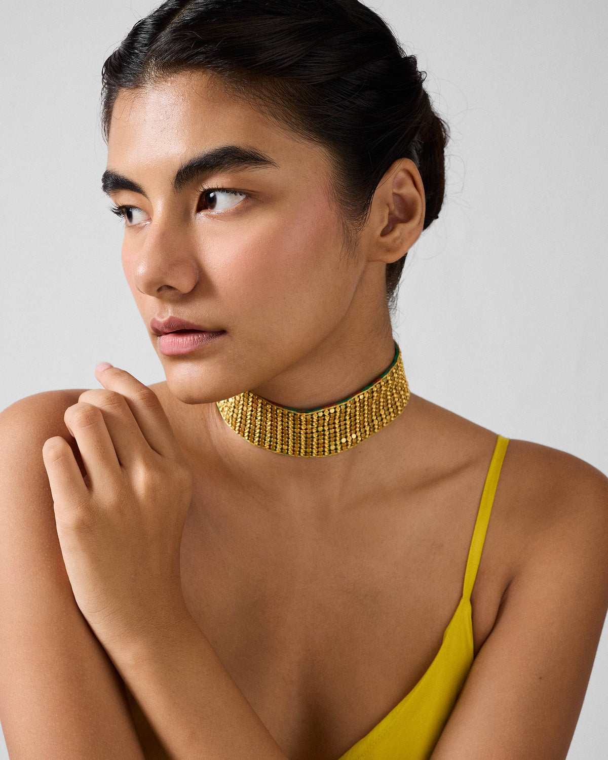 Person wearing a wide gold Chain Mail choker high on the neck.
