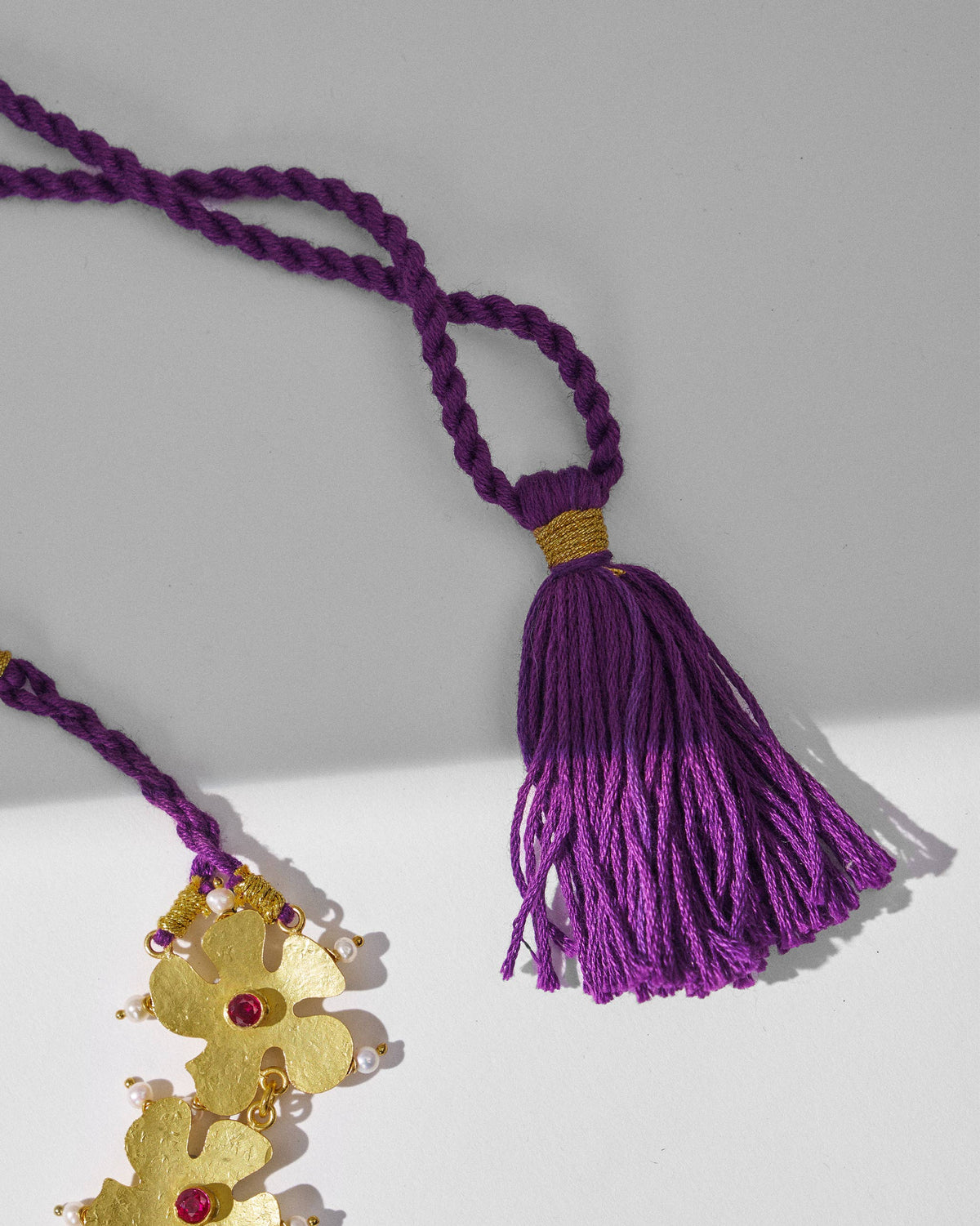 Close-up of a gold phool haar necklace cord, tassel, and floral motifs.