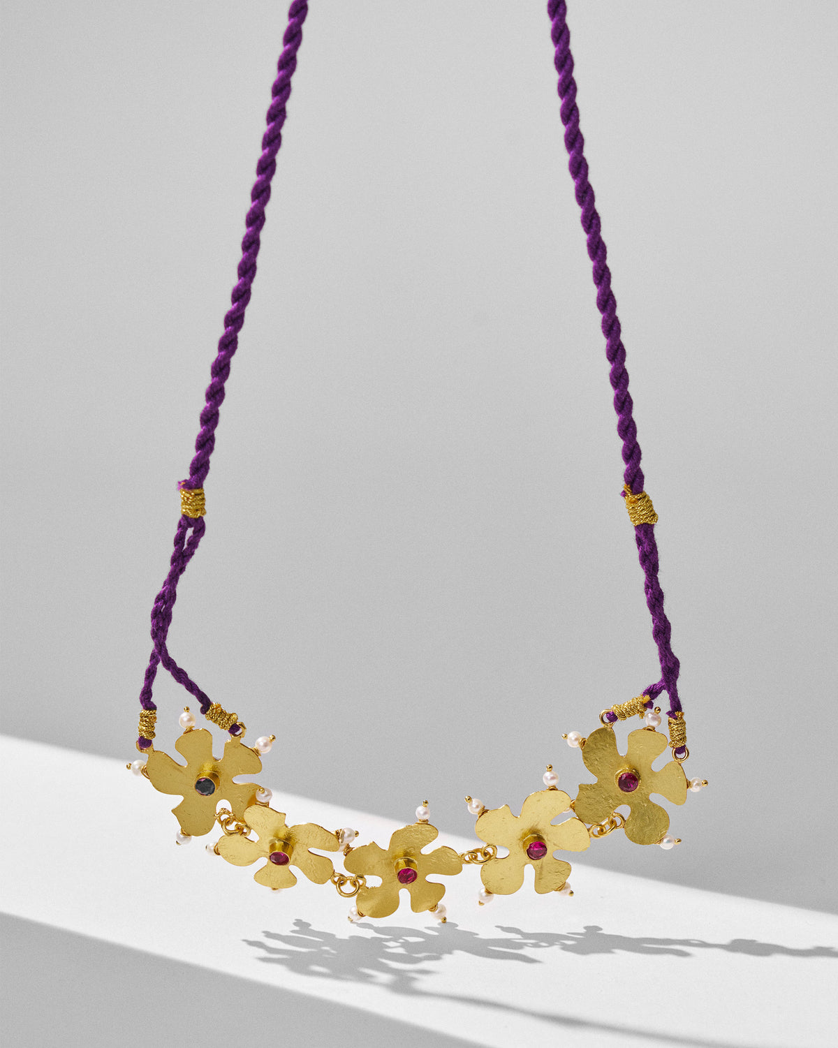Close-up of gold phool haar necklace flowers with red stones and pearls.