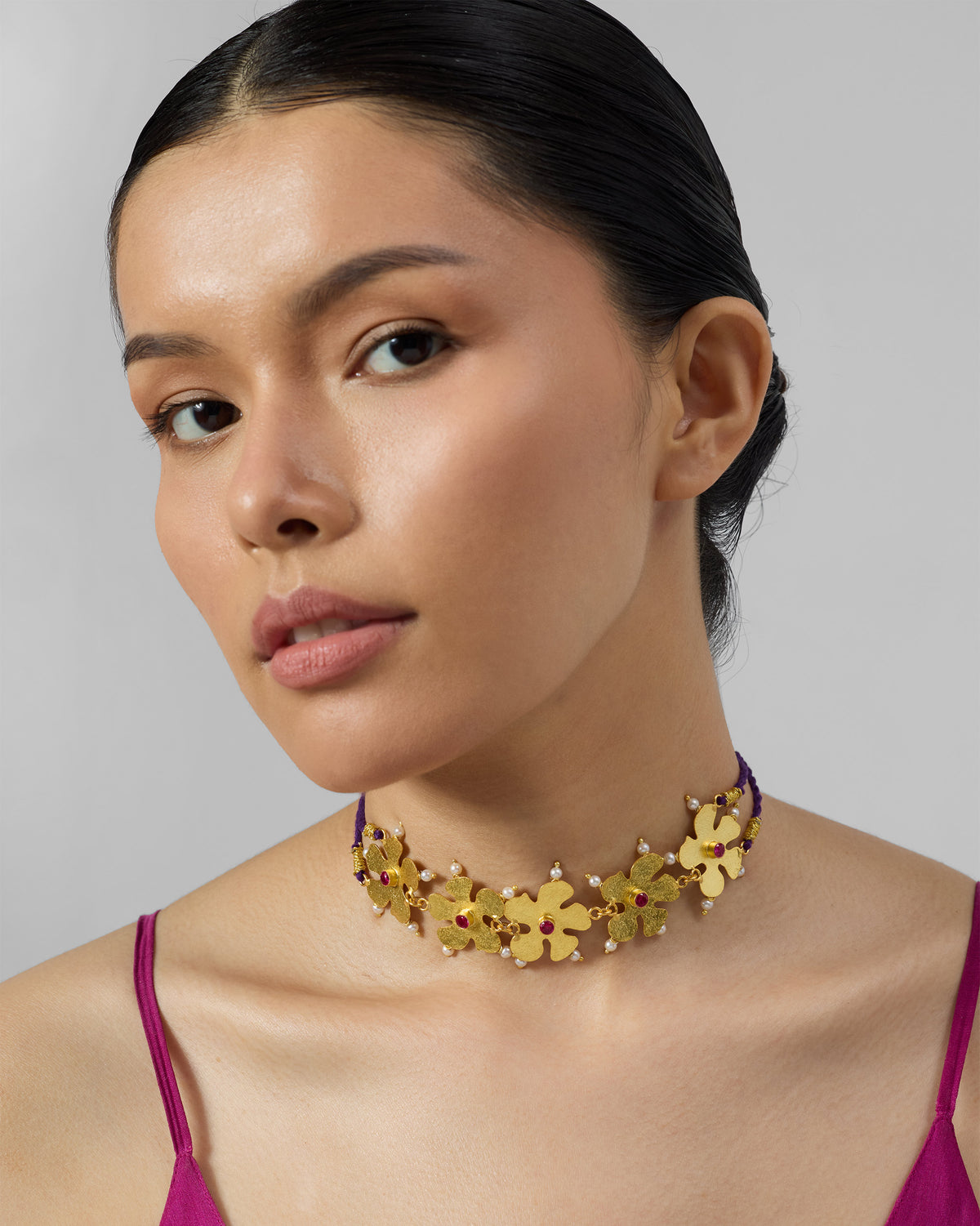 Person wearing a gold phool haar necklace with floral motifs.