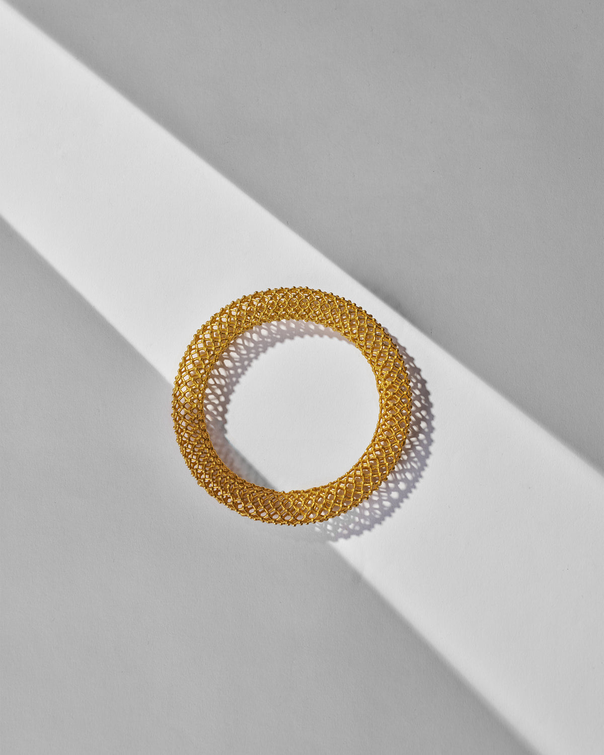 Gold mesh Infinity bangle showing its open lattice form.