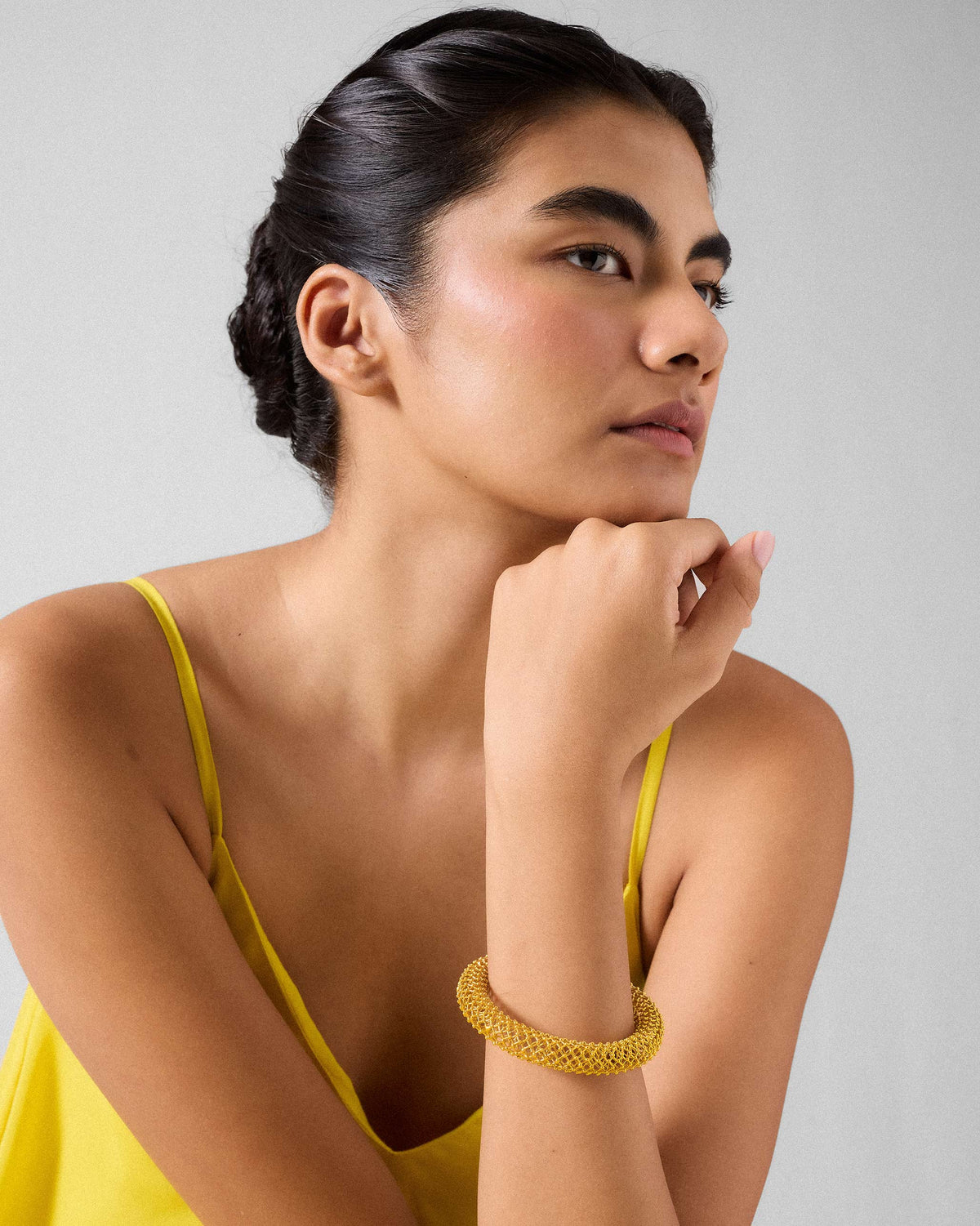 Person wearing a chunky gold mesh Infinity bangle.