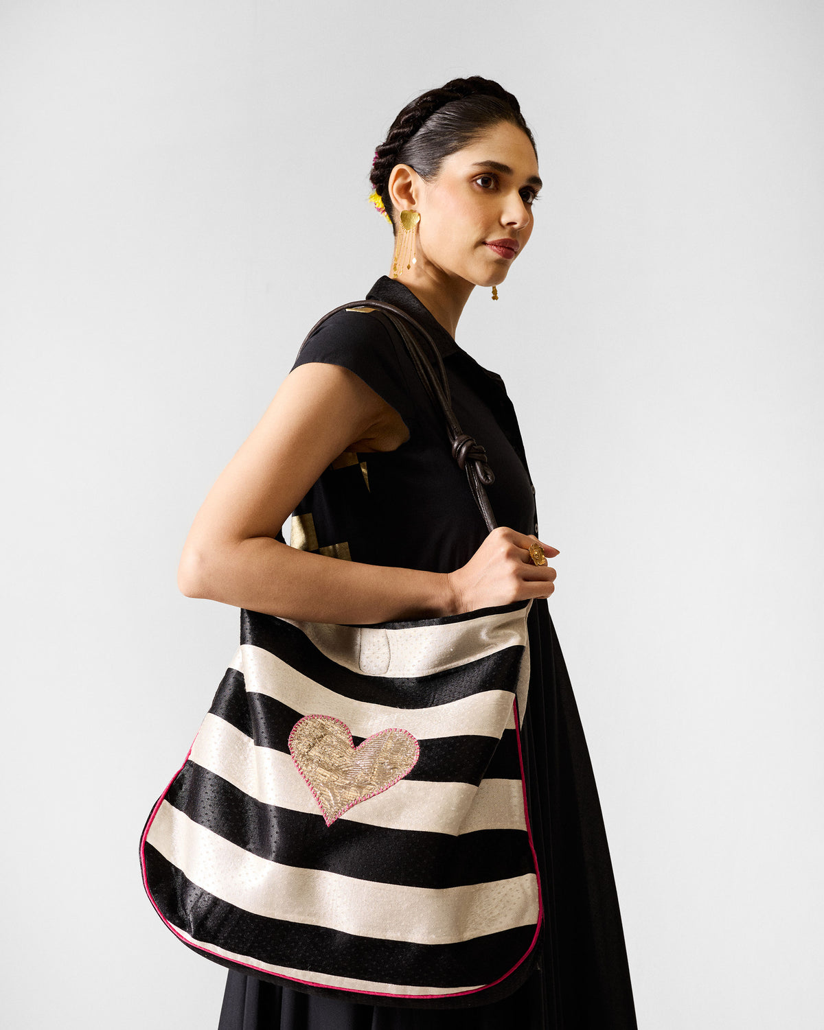Black and ivory Nomad Tote with a gold heart worn on the shoulder.