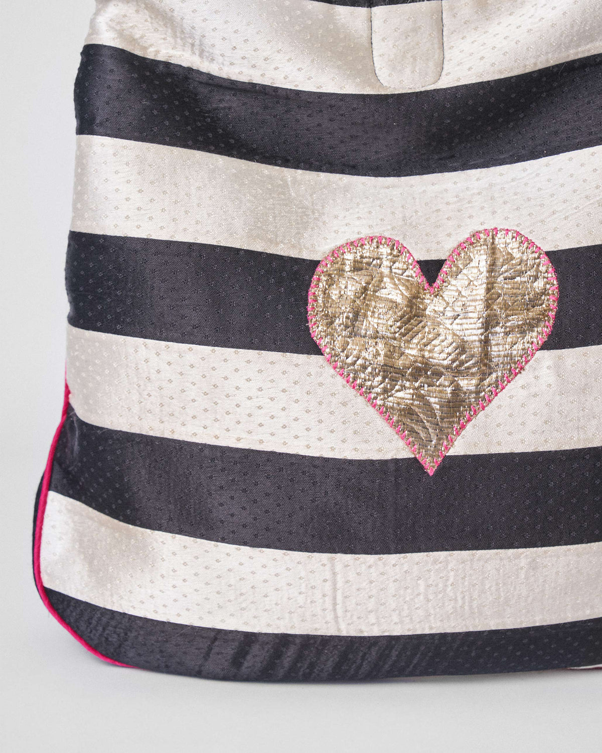 Close-up of a gold heart on a black and ivory Nomad Tote.