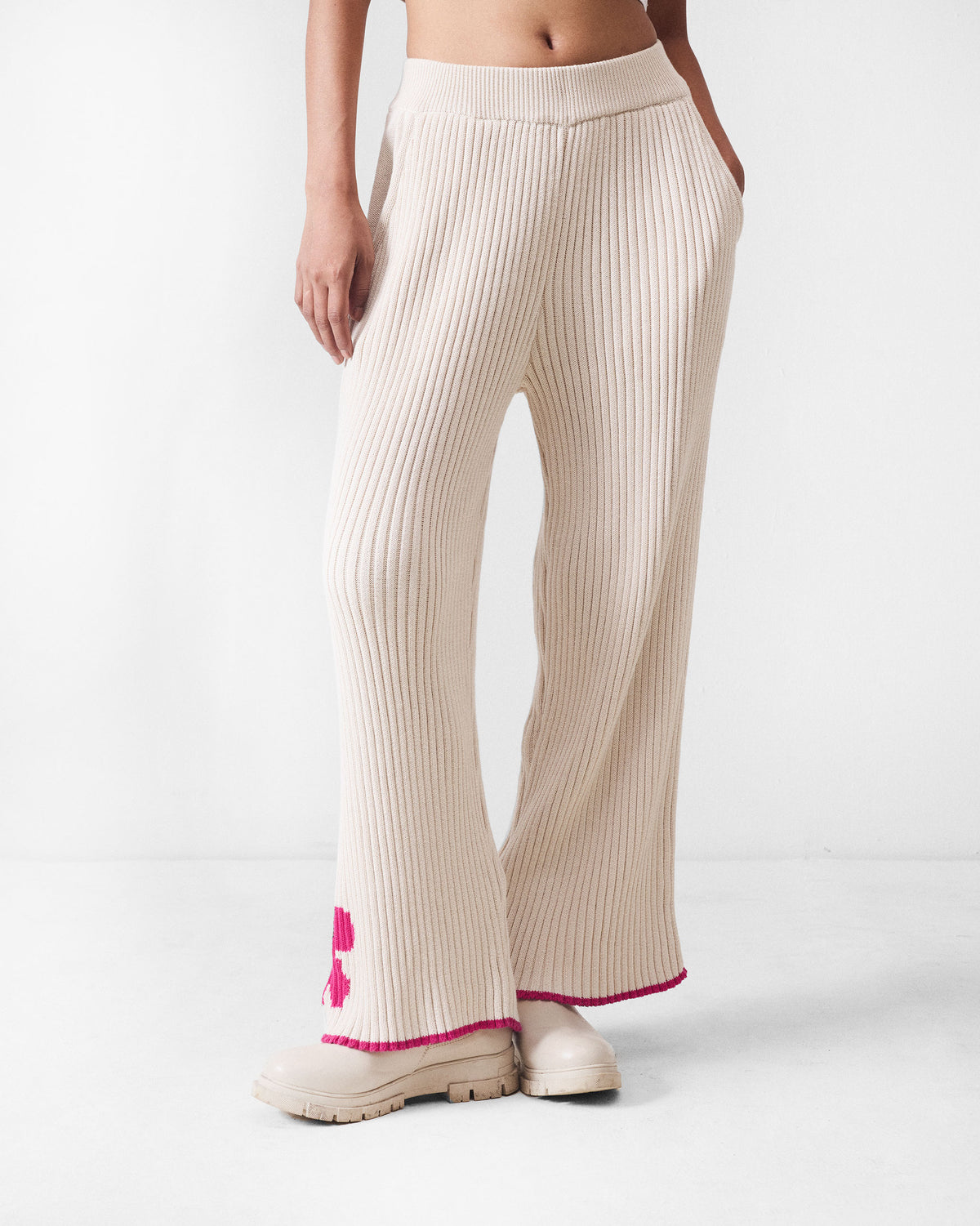 Person wearing ivory rib knit trousers with a pink flower motif.