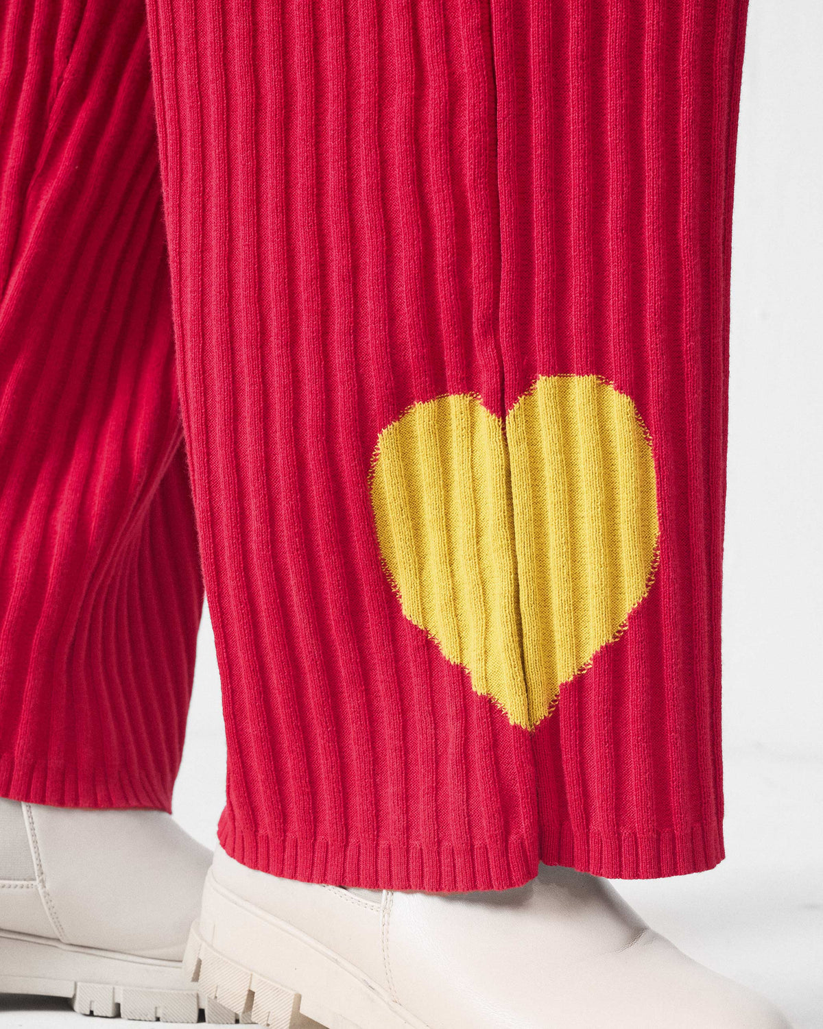 Close-up of red rib-knit pants with a yellow heart near the hem.