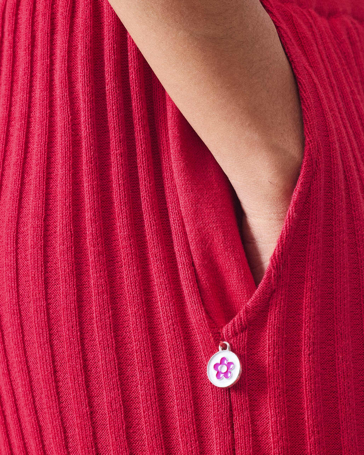 Close-up of red rib-knit pants with a flower coin at the pocket.