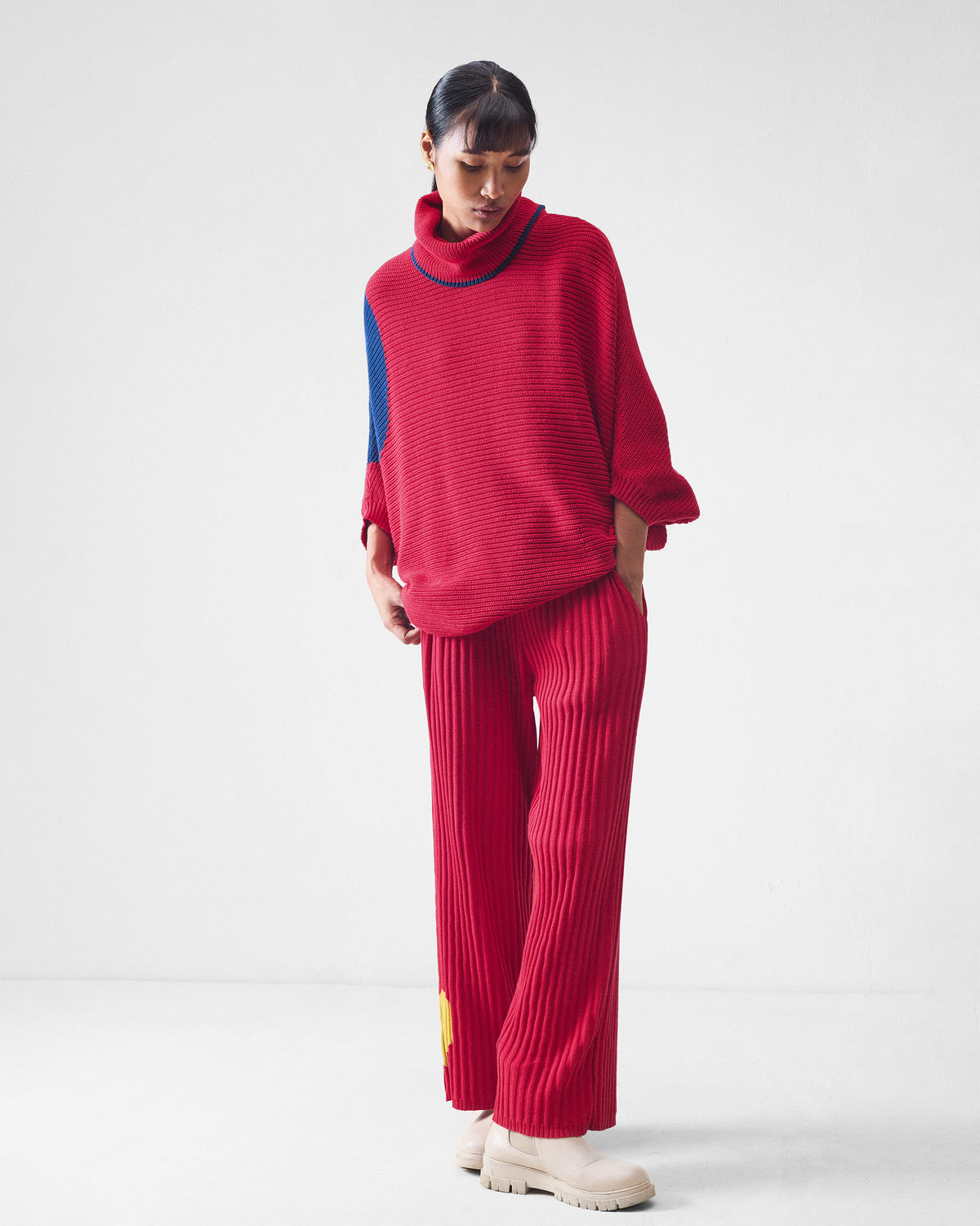 Person wearing red rib-knit wide-leg pants with a yellow heart detail.