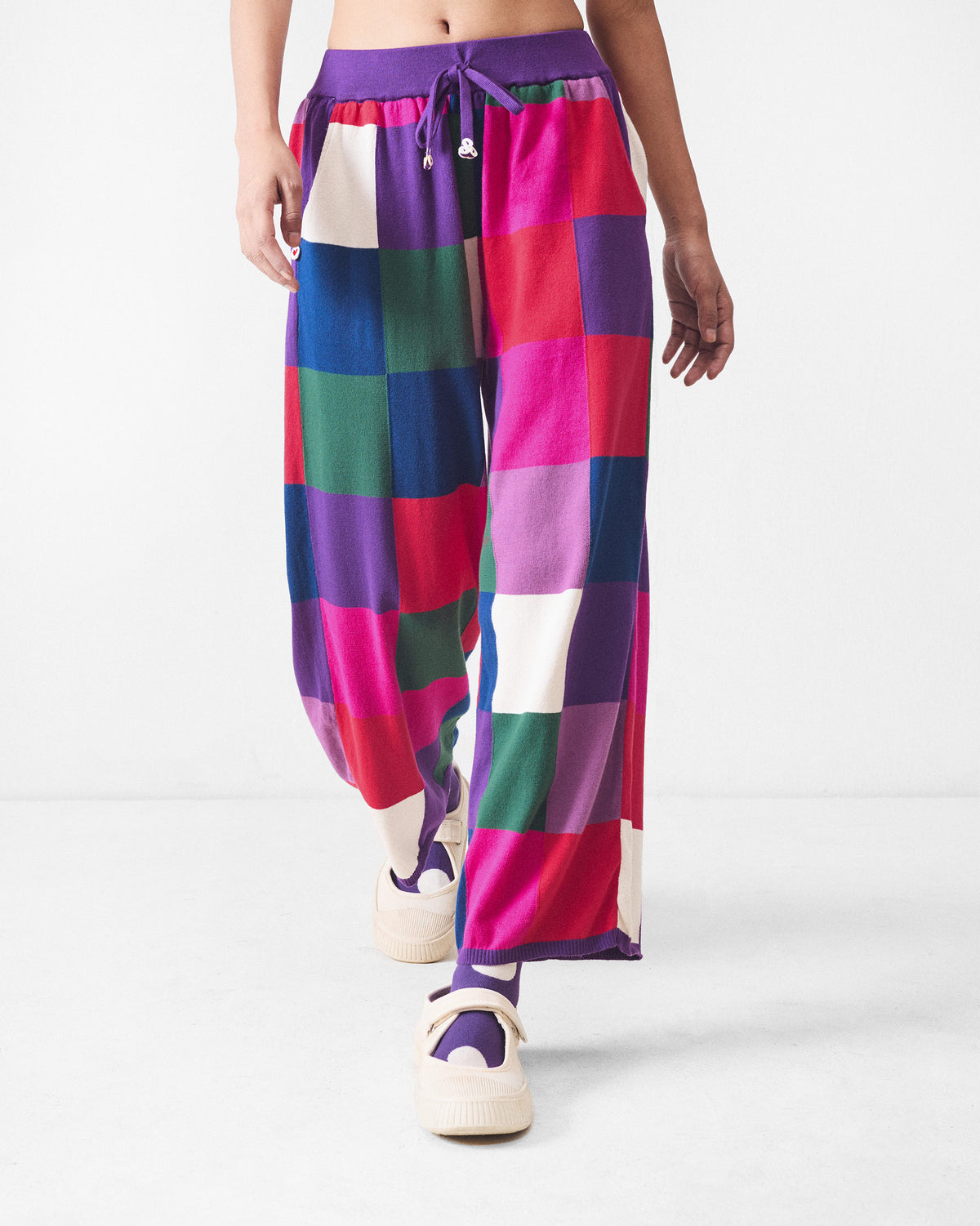 Person wearing multicolour check knit trousers with a purple drawstring waist.