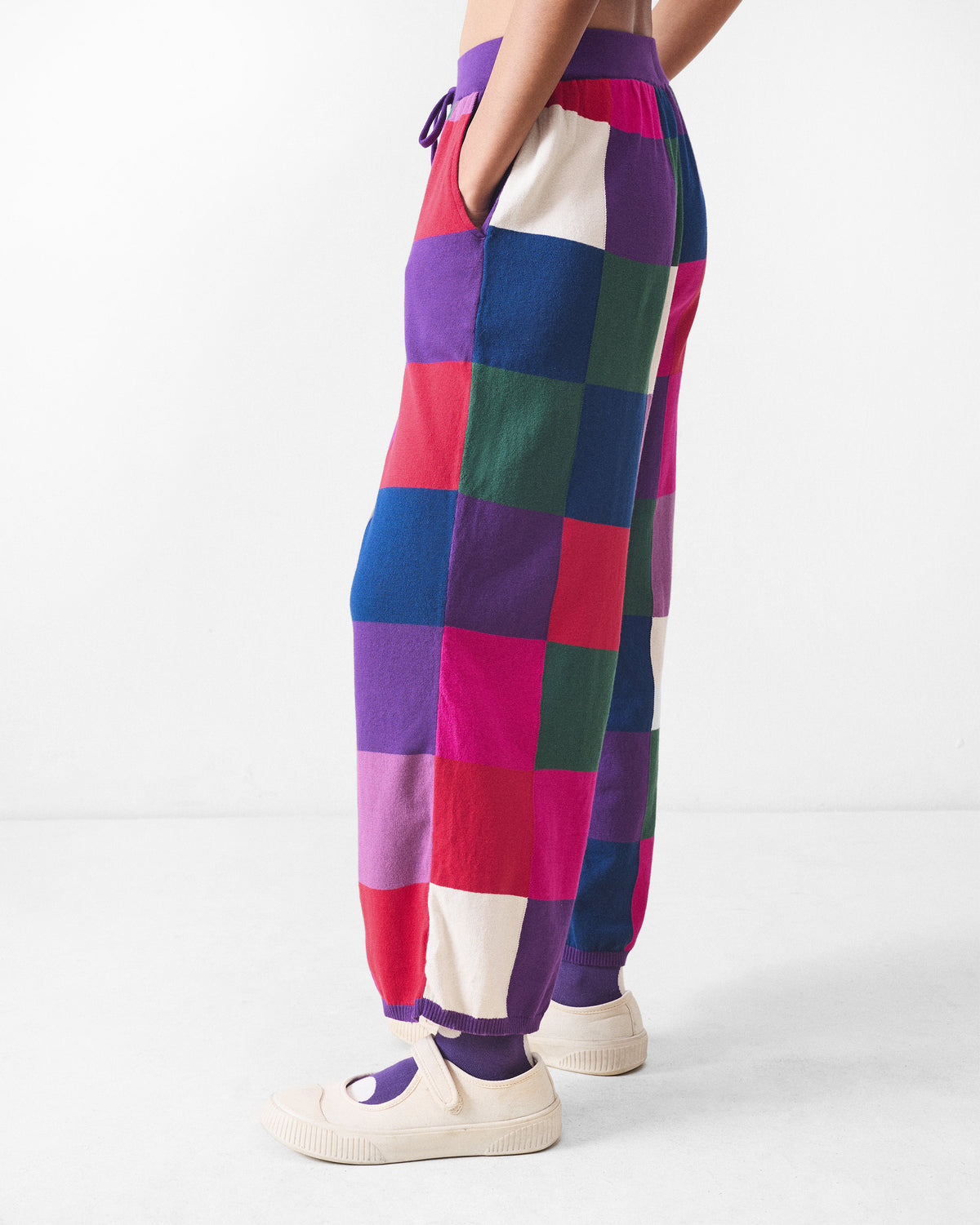 Side view of multicolour check knit trousers with a purple ribbed cuff.