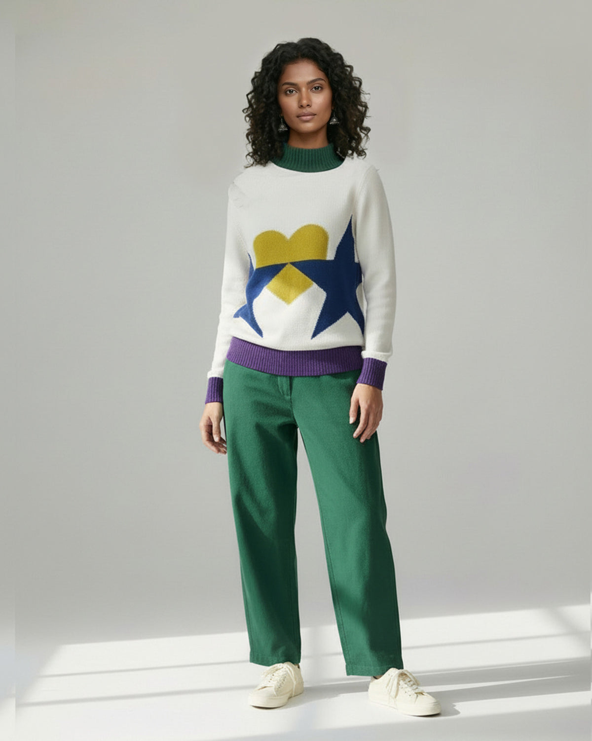 Person wearing an ivory Crew Neck Sweater with a yellow heart and navy stars.