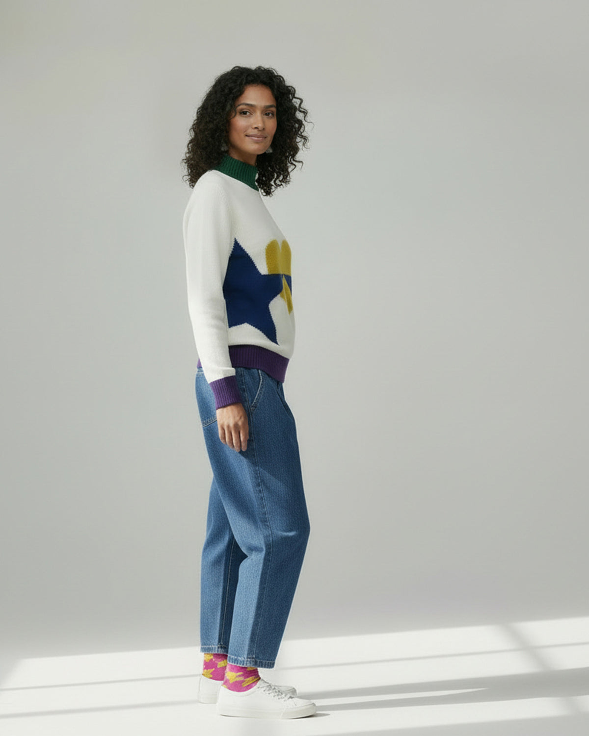 Side view of an ivory Crew Neck Sweater with a navy star on the side.