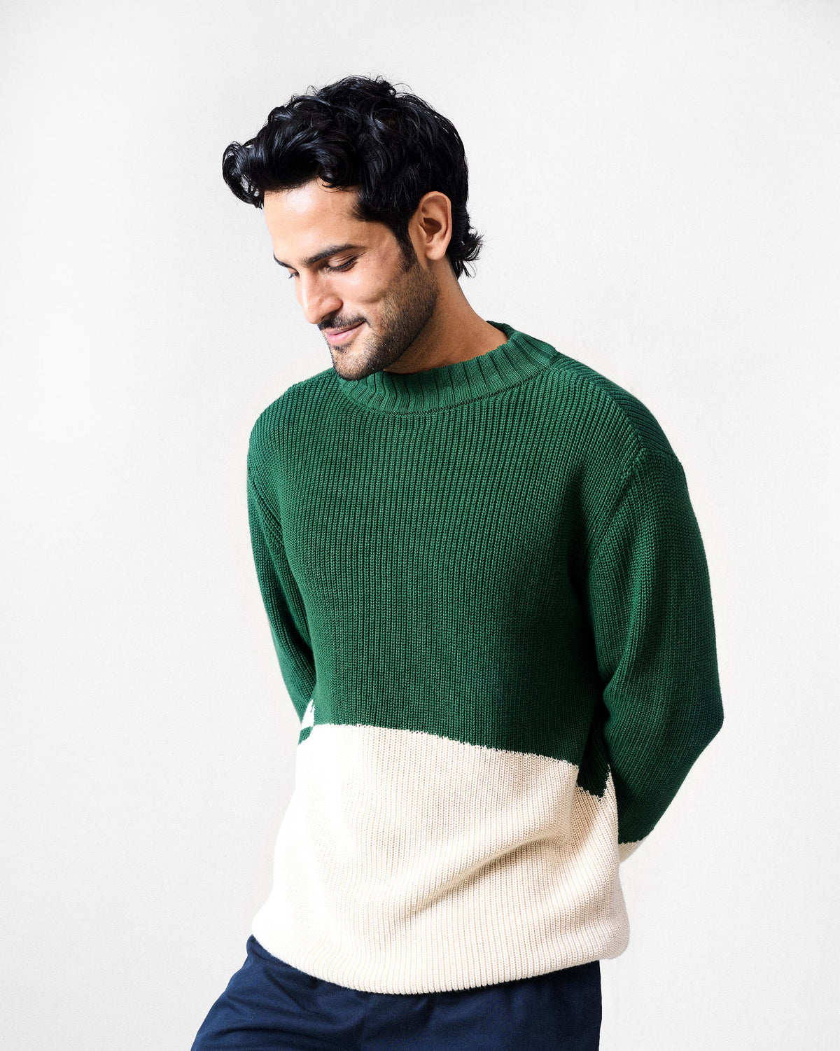 Person wearing a green and ivory colour-block crew neck sweater.