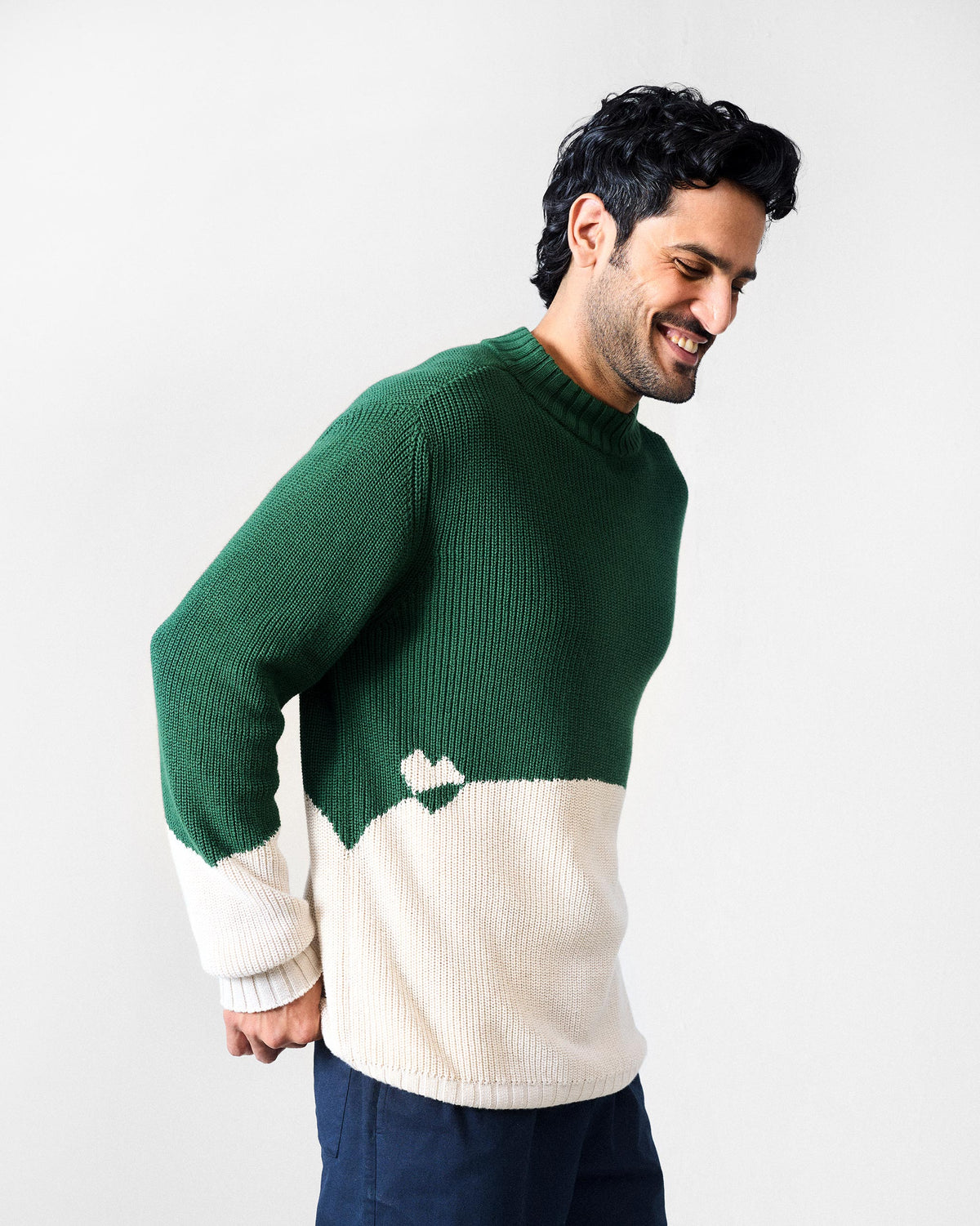 Side view of a green and ivory ribbed crew neck sweater.