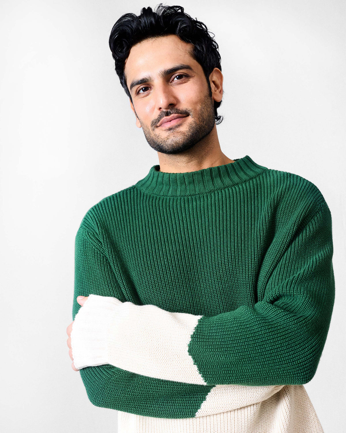Person wearing a green and ivory ribbed crew neck sweater with colour-block sleeves.