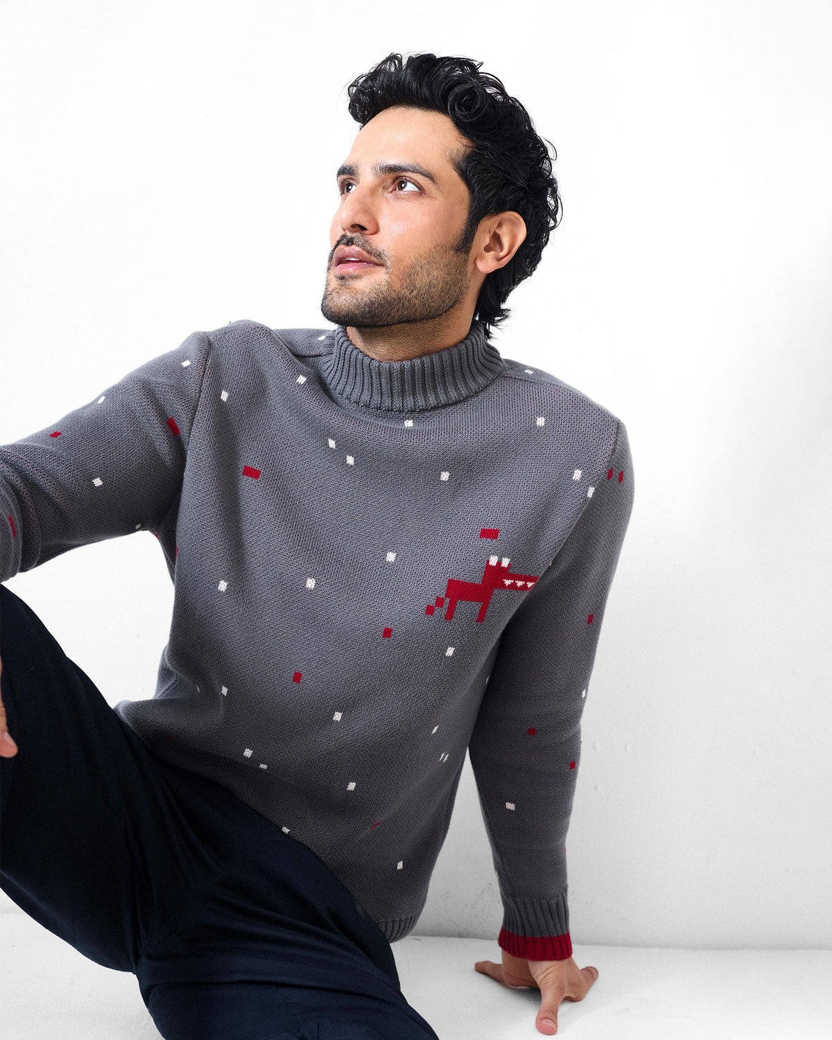 Person wearing a charcoal Crew Neck sweater with a pixel dino motif and red cuff tipping.