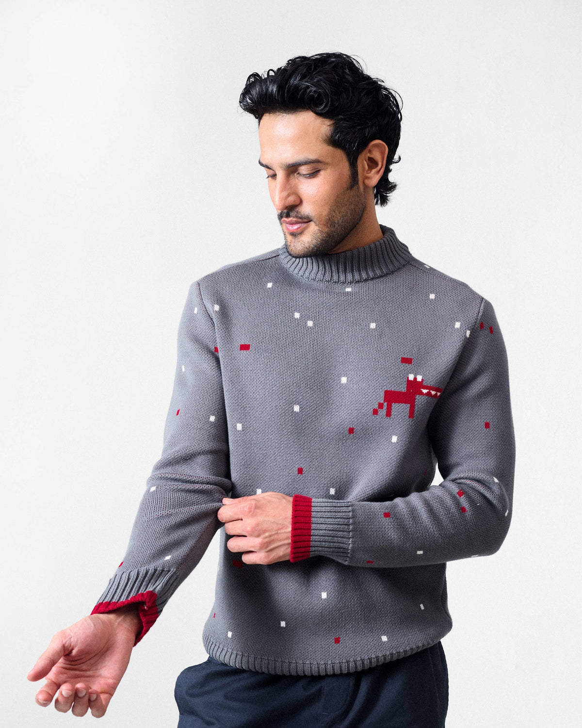Person wearing a charcoal Crew Neck sweater with red cuff tipping and a pixel chest motif.