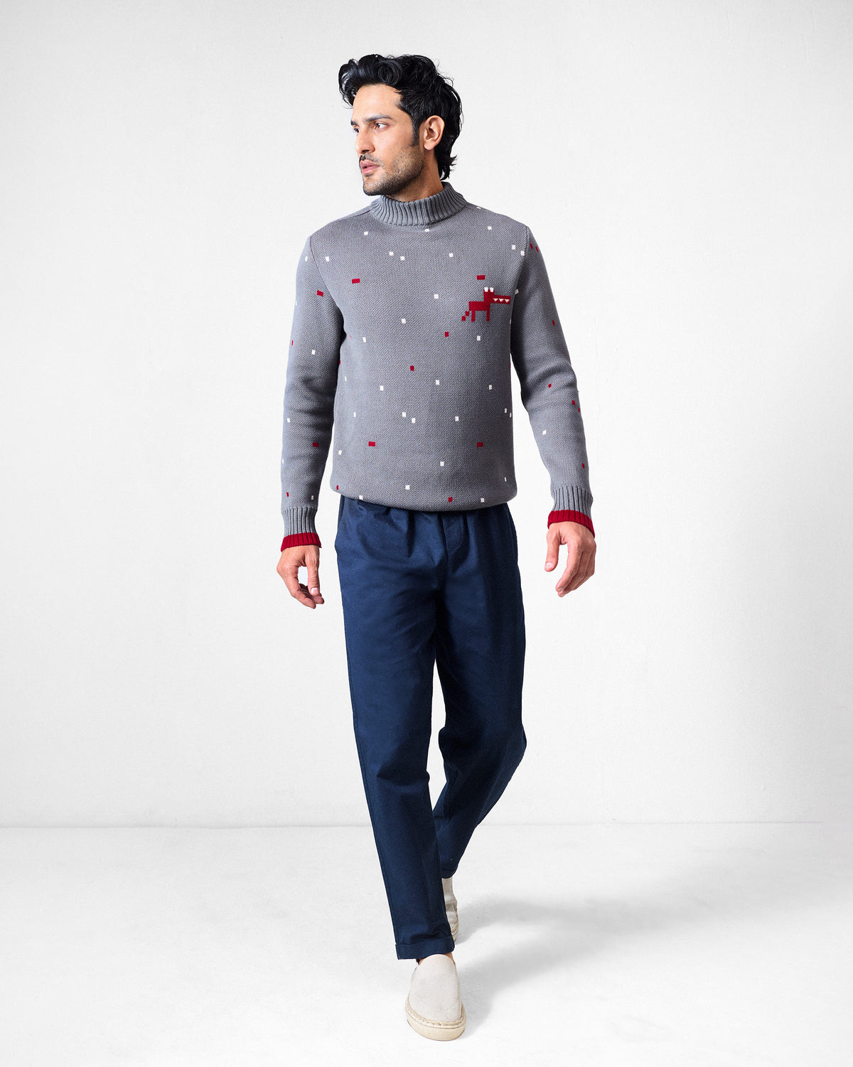 Person wearing a charcoal Crew Neck sweater with a red pixel motif and red cuff tipping.