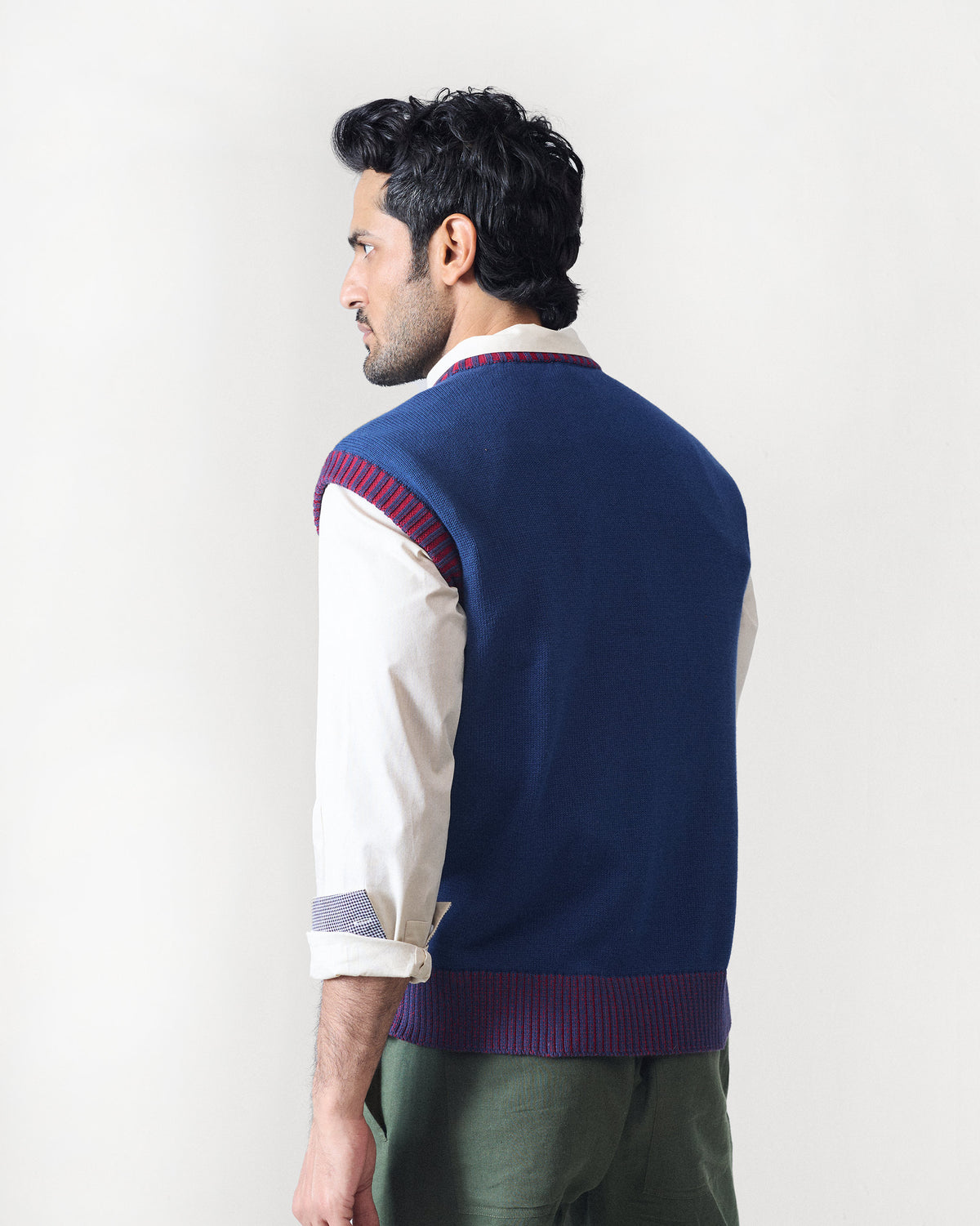 Back of a navy sleeveless Pixel Sweater with maroon striped ribbed edges.
